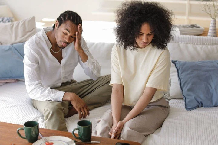 Couple sitting together but appearing emotionally disconnected, reflecting relationship tension and difficulty reaching one another.