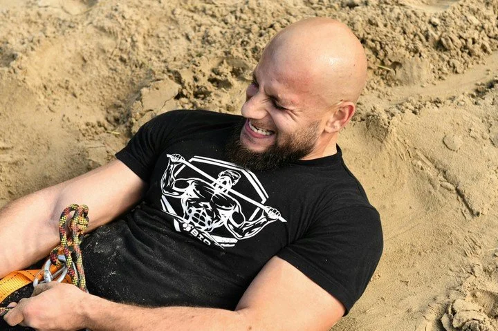 Man straining while pulling a rope in sand, representing pressure, stress, and internal struggle often addressed in therapy for men in San Francisco.