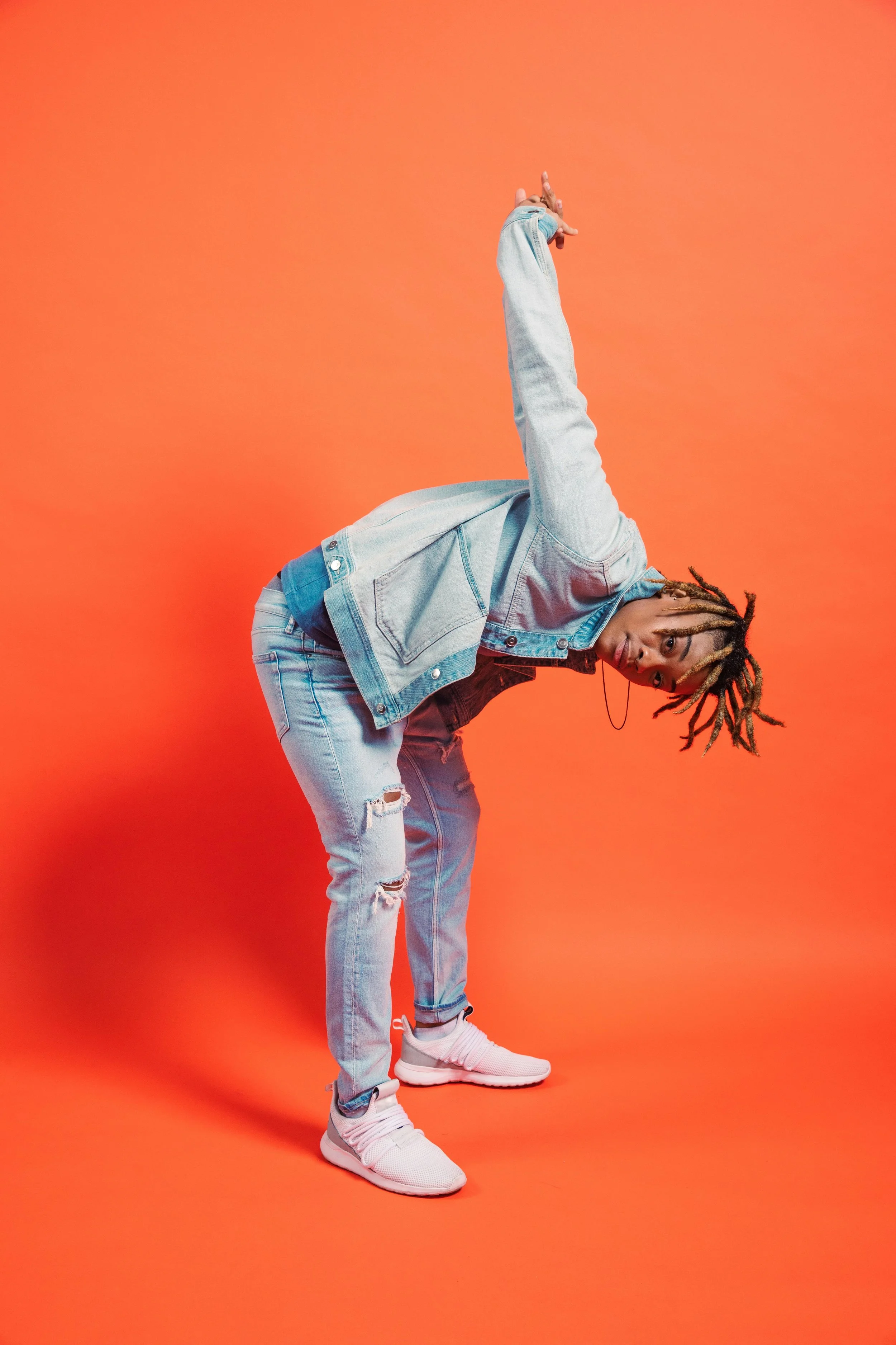 A gender-non-conforming young person posing boldly against a bright backdrop, symbolizing confidence and authentic self-expression.