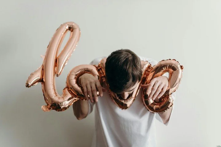 Person holding balloon letters spelling “love” while looking downward, symbolizing emotional disconnection, loss of attraction, and intimacy struggles explored in psychodynamic psychotherapy in San Francisco.