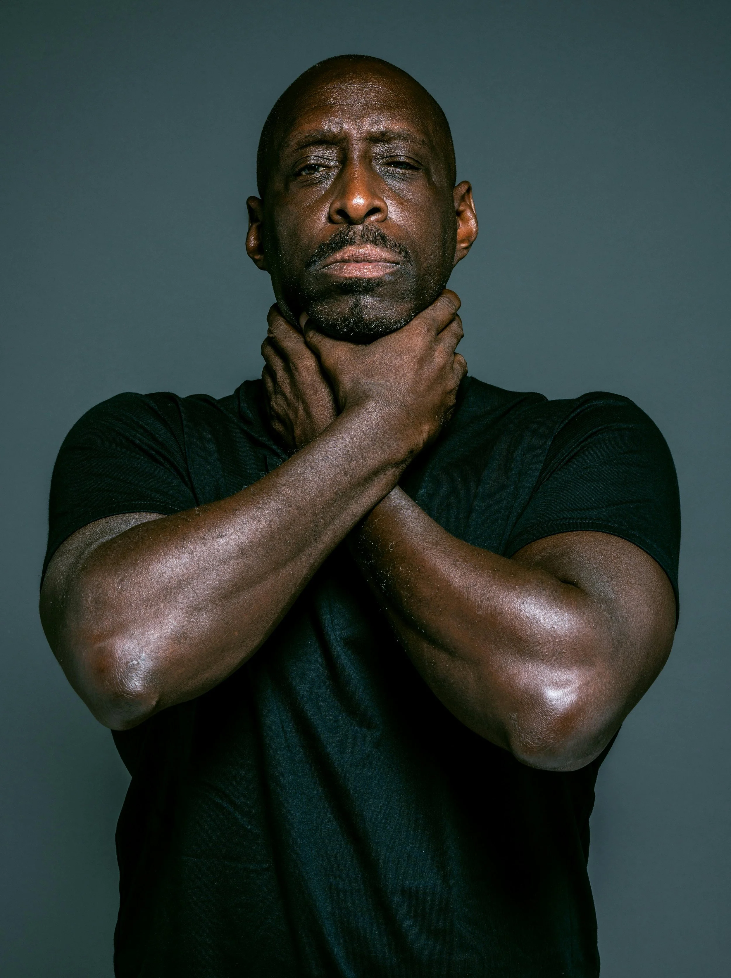 A man holding his hands firmly at his neck and chest, symbolizing the internal pressure and rigidity often associated with machismo and traditional masculinity norms.