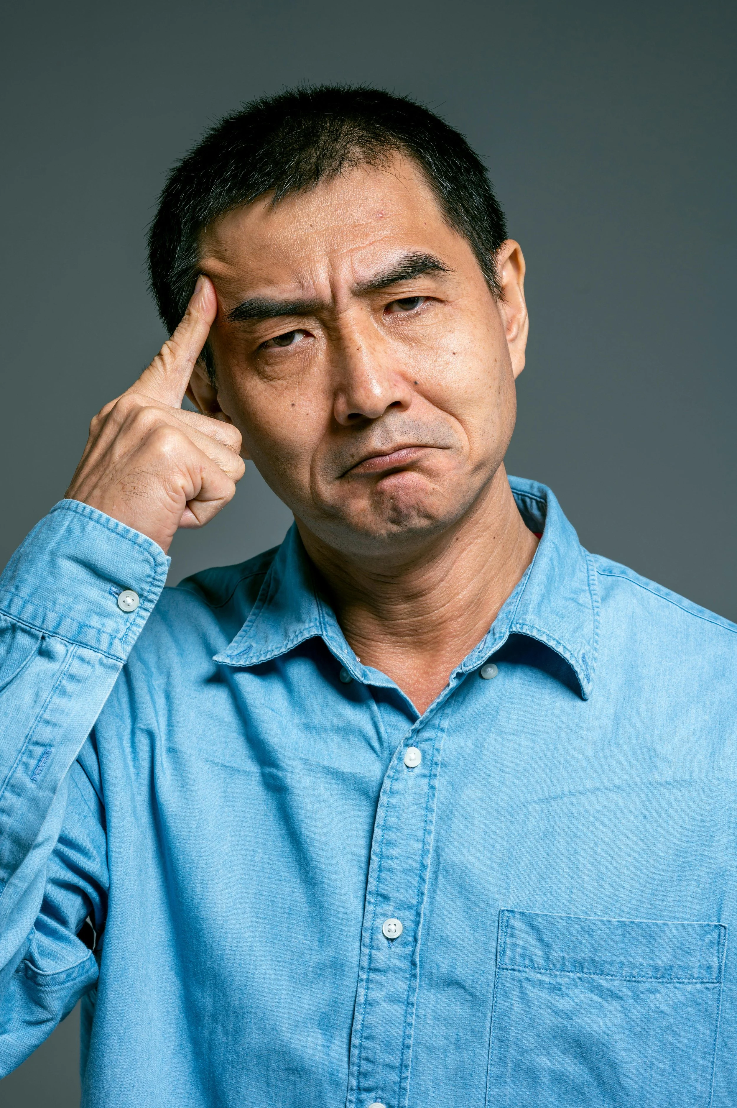 A man touching his temple with a thoughtful, concerned expression, symbolizing the reflection and challenges men face during midlife transitions in their 40s and 50s.