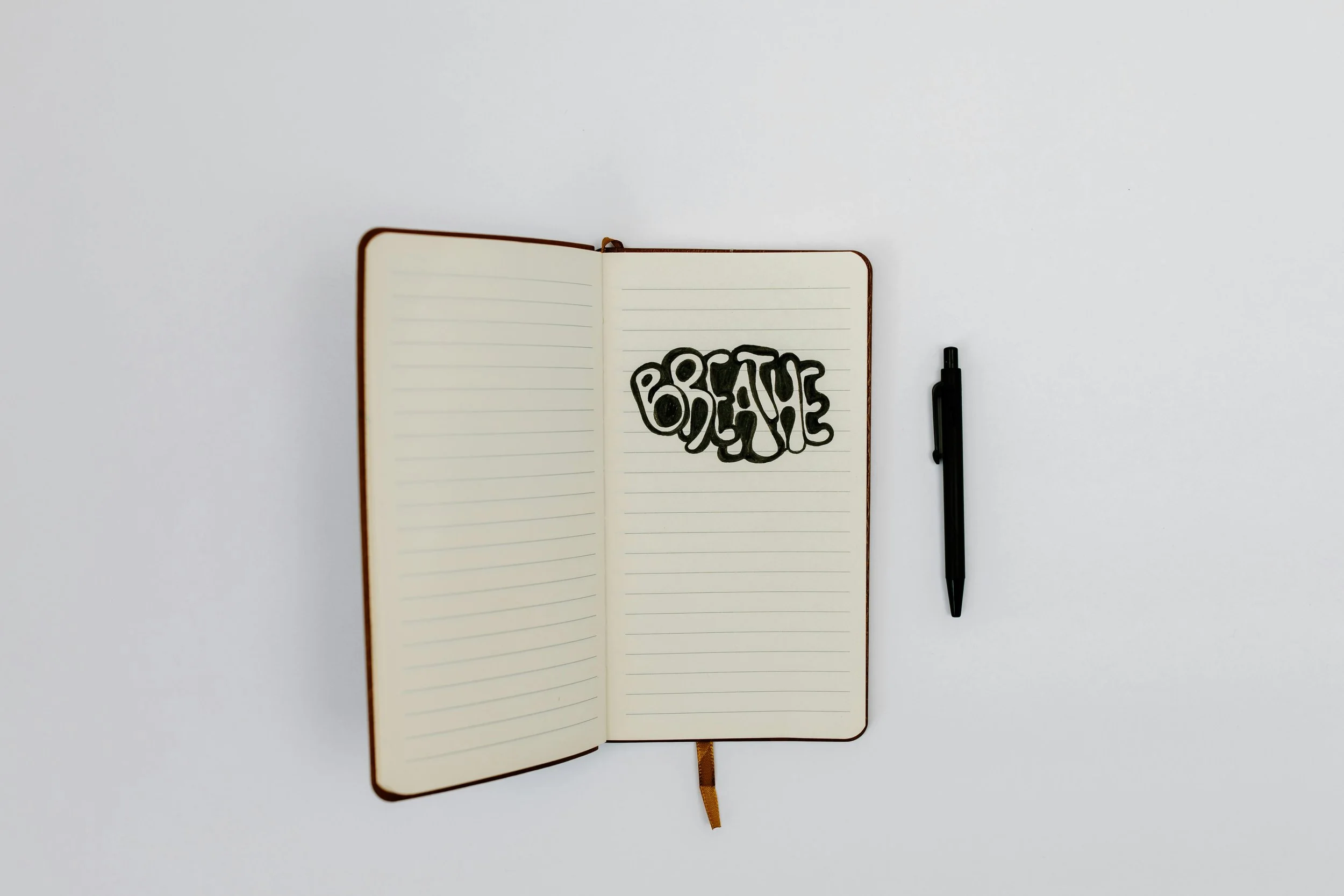 An open notebook with the word “breathe” written inside, symbolizing the calming shift from perfectionism to self-compassion.