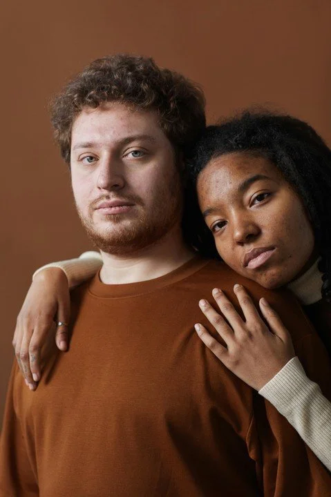 Multicultural couple standing close together with one partner resting their head on the other’s shoulder, representing emotional connection, intimacy, and relationship dynamics explored in relationship counseling in San Francisco.
