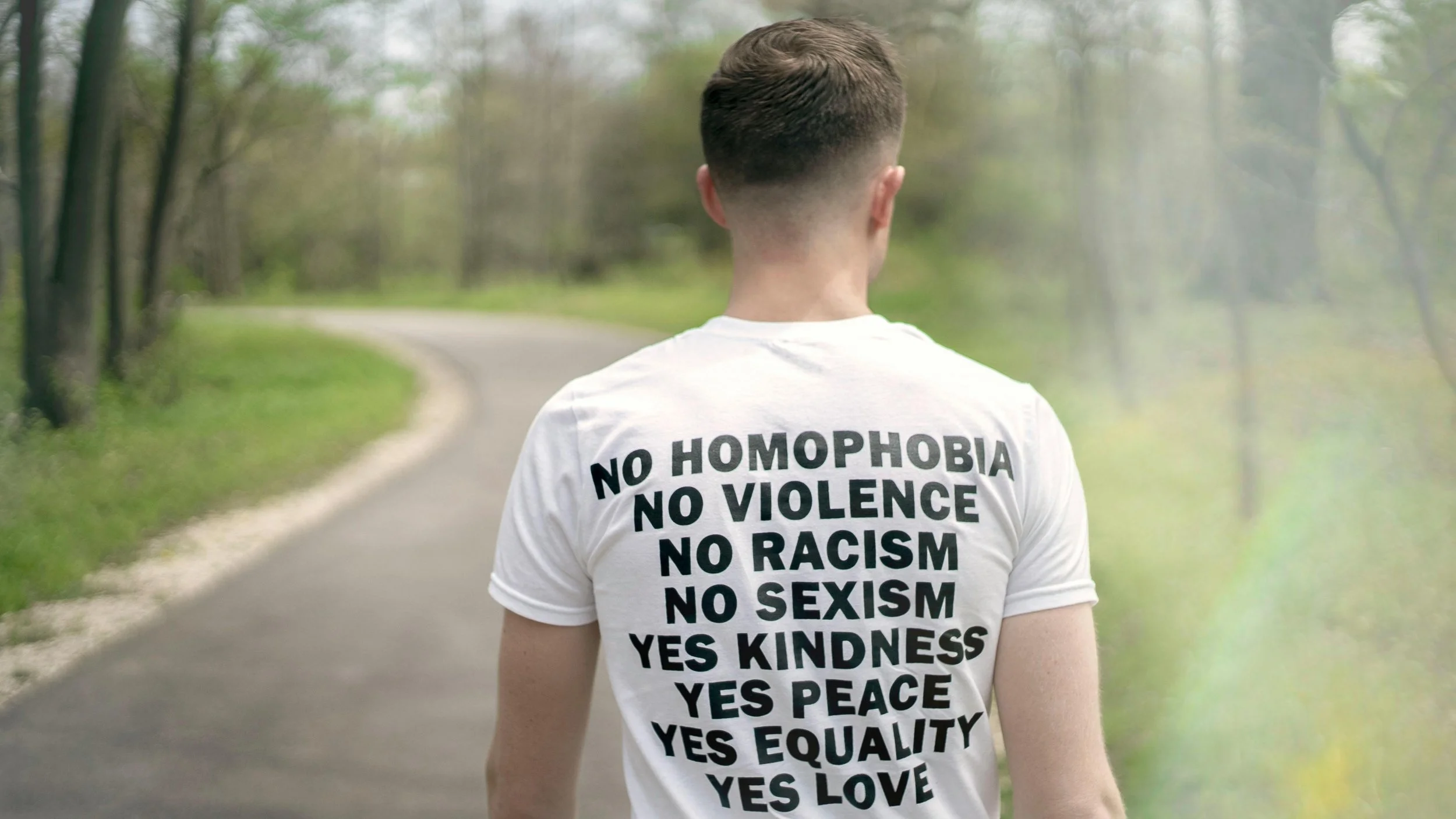 A person walking outdoors wearing a shirt promoting equality and kindness, symbolizing the values at the core of LGBTQ-affirming therapy.