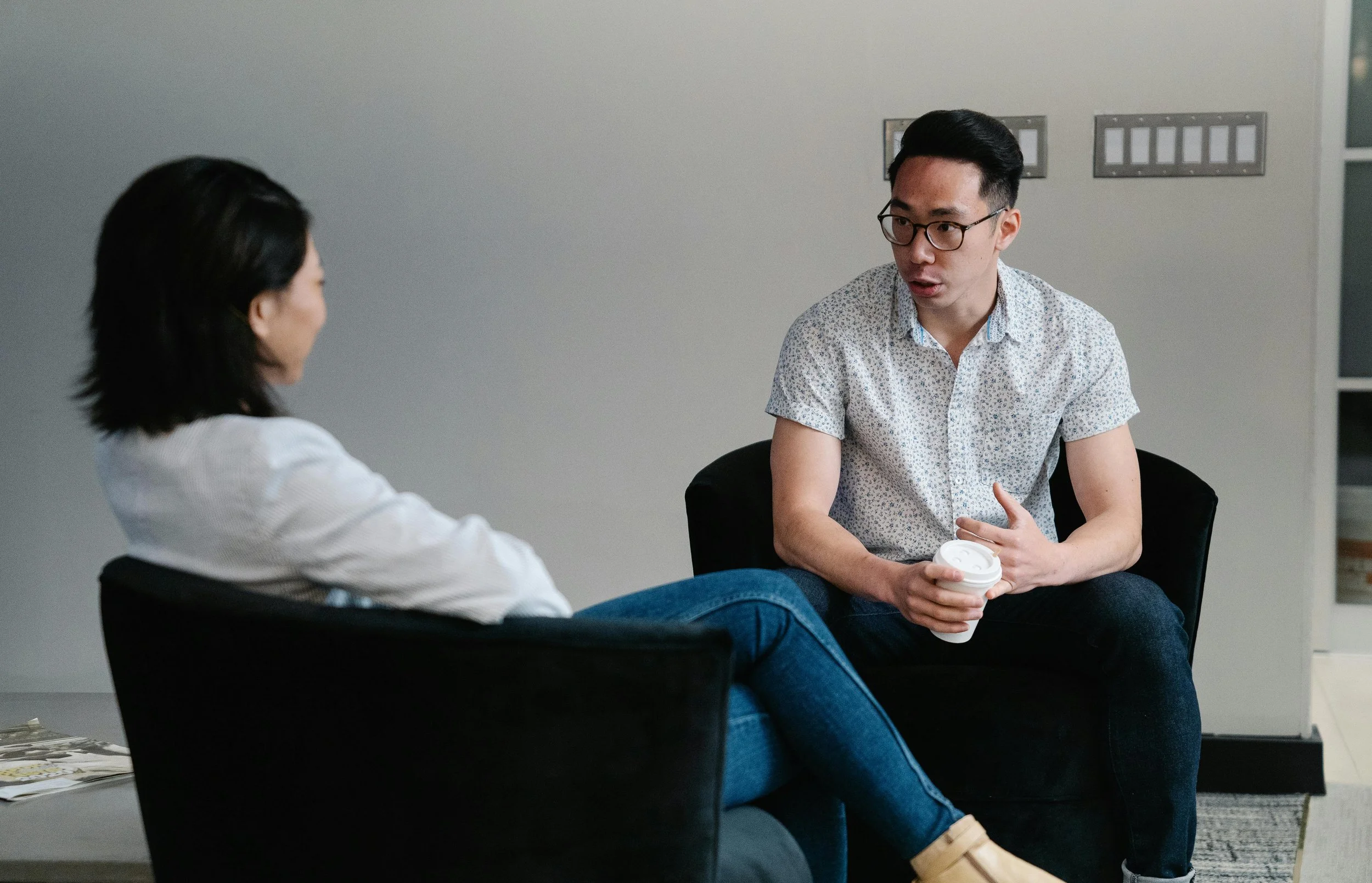 Two people engaged in a thoughtful conversation during a session, symbolizing how attachment patterns from early relationships are explored in psychodynamic therapy.