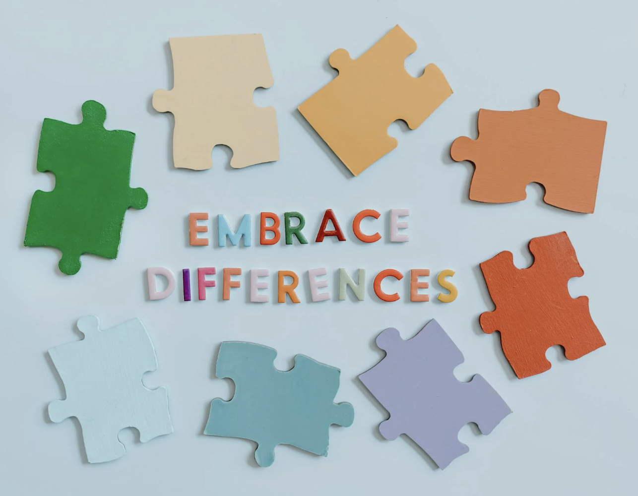 Colorful puzzle pieces surrounding the phrase “Embrace Differences,” symbolizing the intersection of queer identity and neurodiversity.