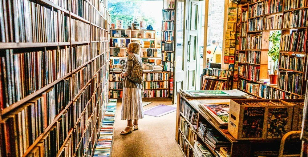 bookstore edited horizontal woman looking at bookshelves - unsplash - july 2026.jpg