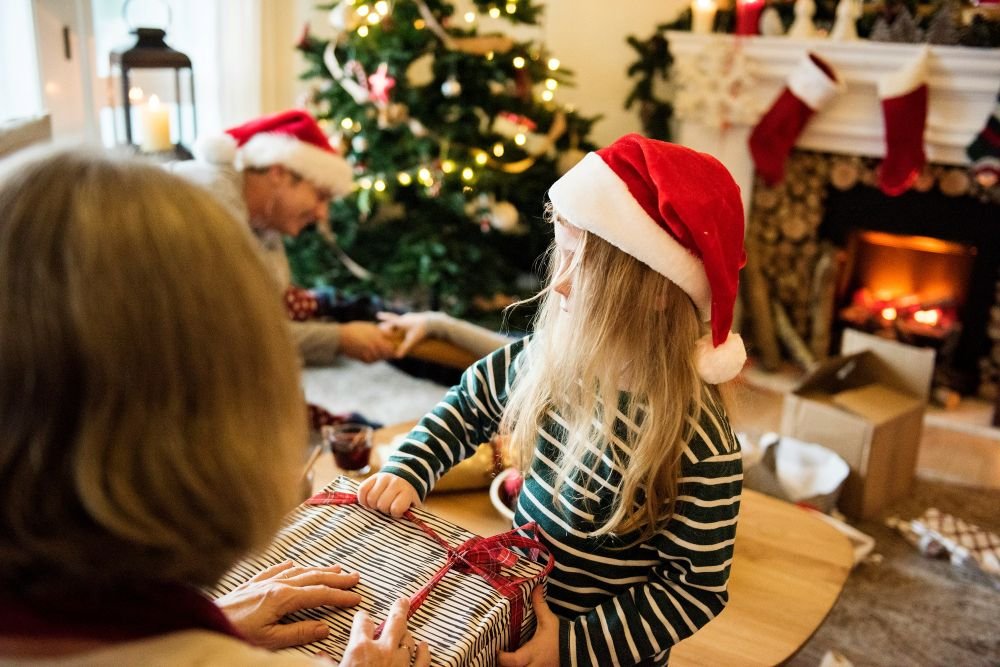 little girl in santa hat opening presents
