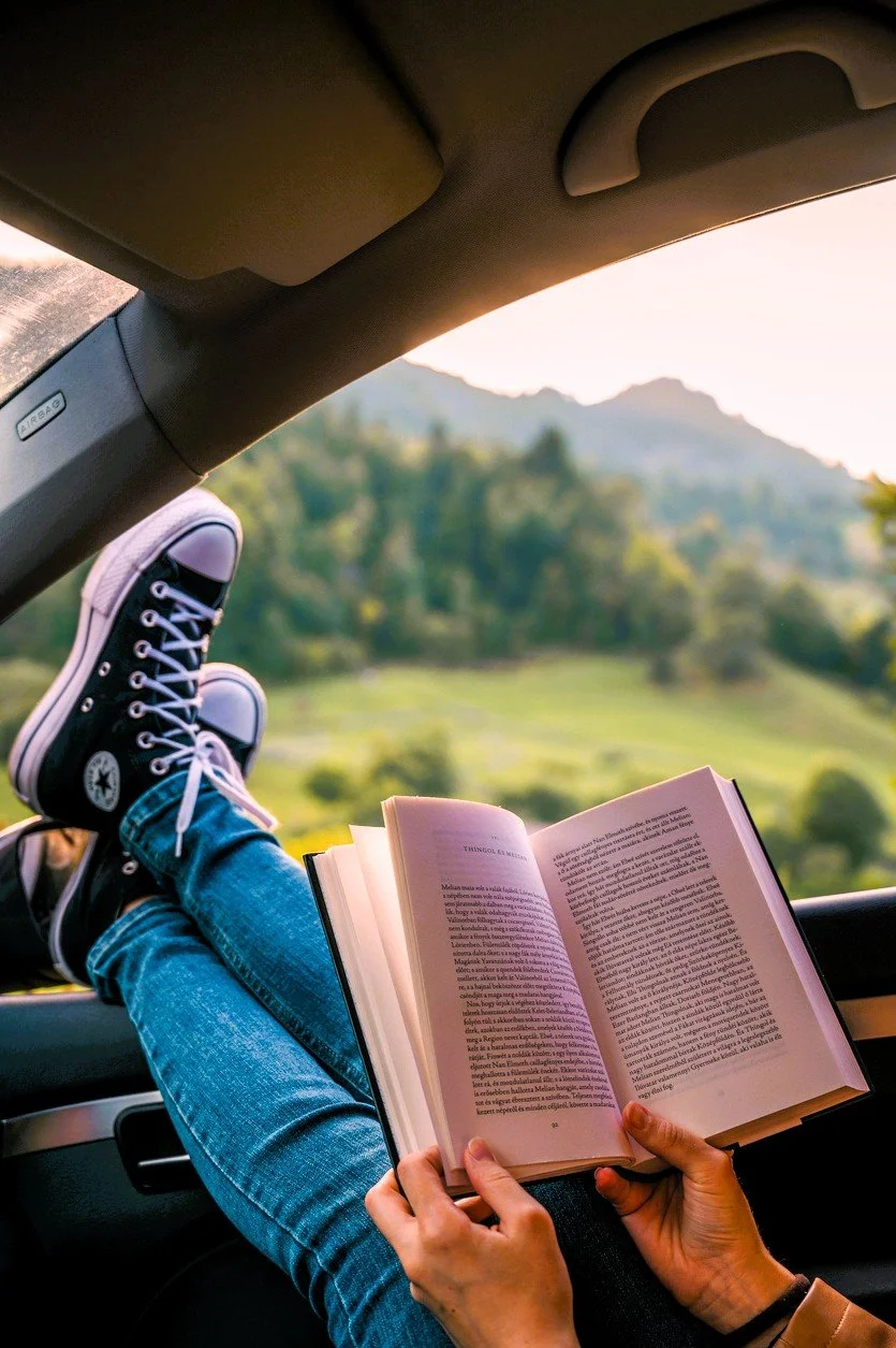 man reading with feet up looking at green mountain view