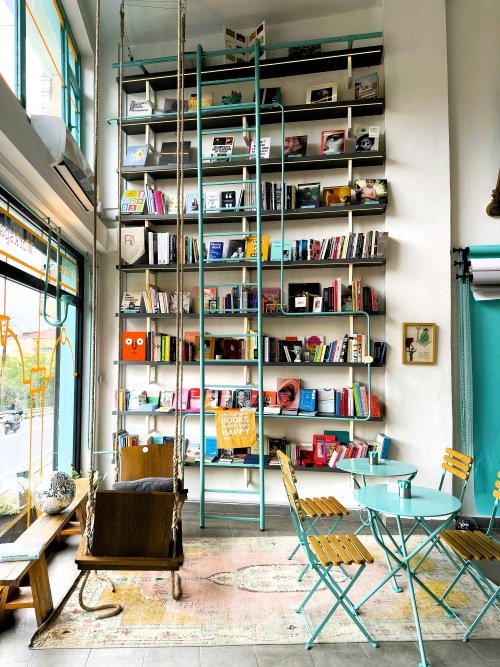 tall bookstore shelf with ladder in sunny front of store