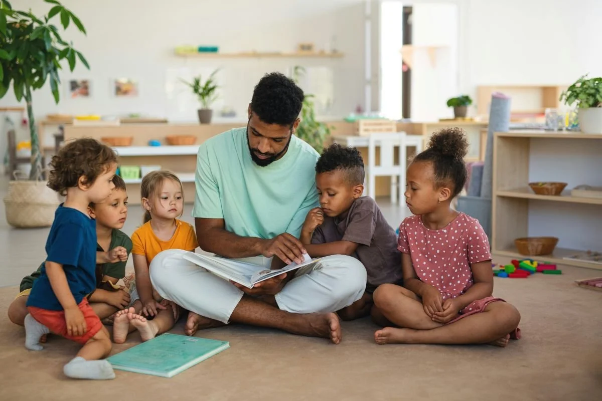 man reading on floor with five kids