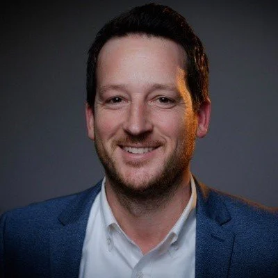 A dark haired caucasian man smiling for a headshot
