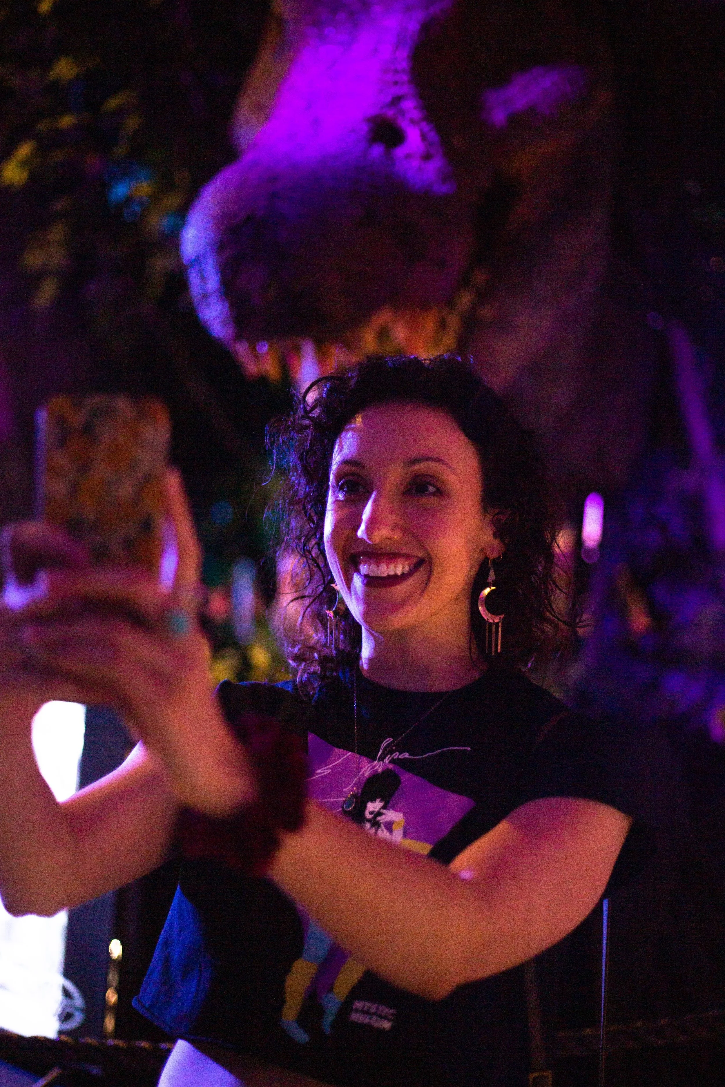 A dark haired young woman taking a selfie in front of a large (fake) dinosaur