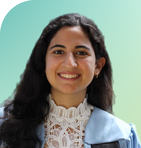 Young woman smiling with white blouse and blue graduation gown and black hair against a green background.