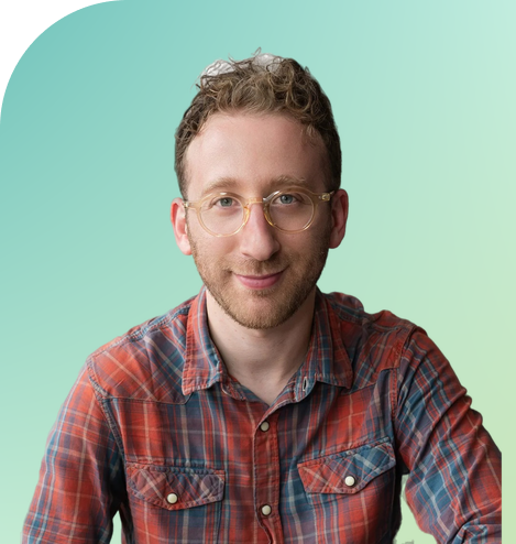 Professional man with red hair and round glasses in a red and blue plaid shirt smiling against a gradient background.