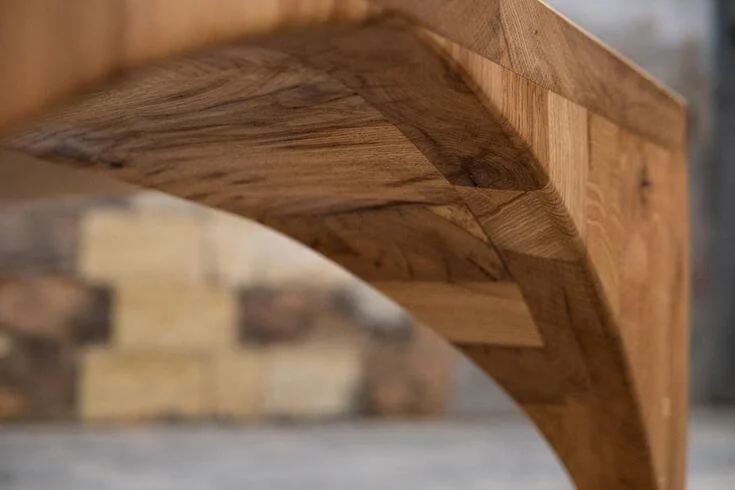 Zoom sur une table en bois massif, avec une ligne courbée inspirée du style gothique