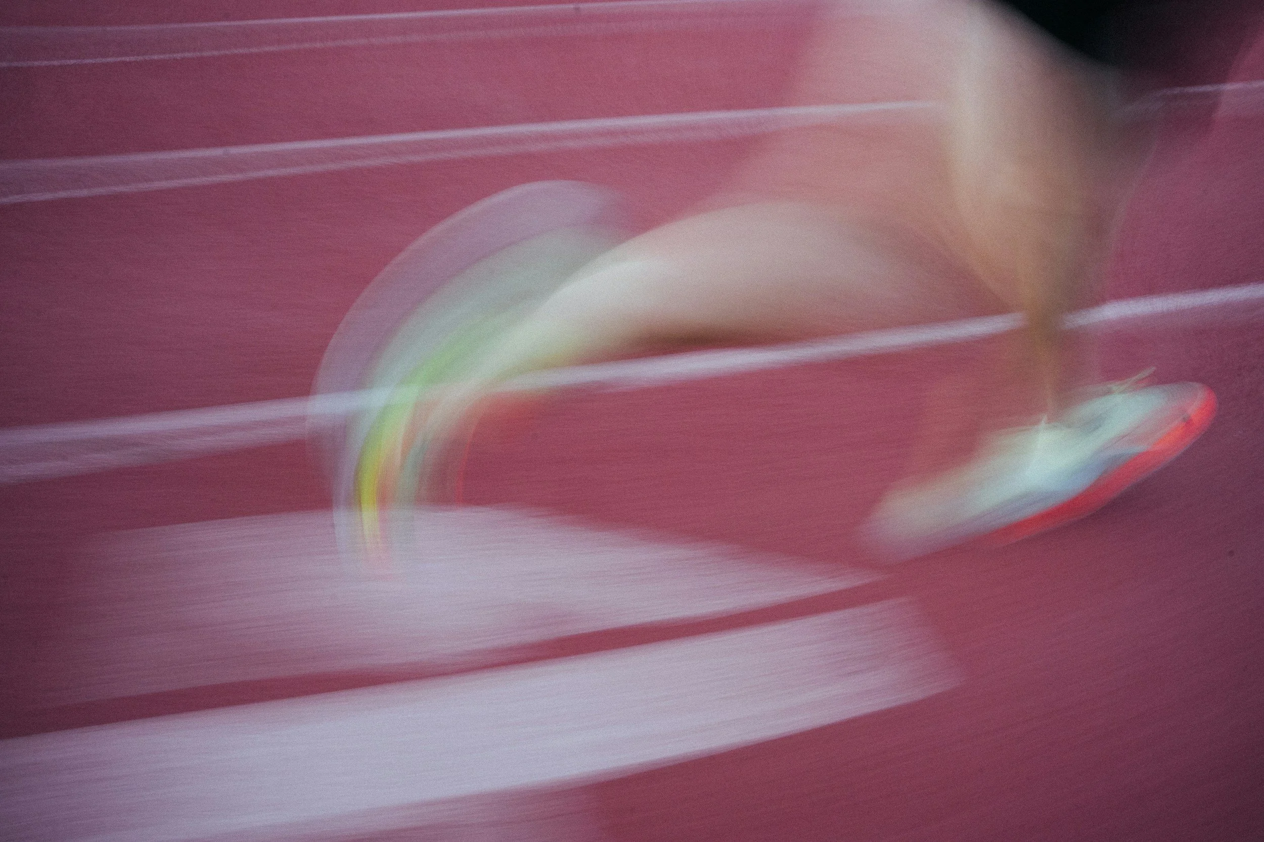 Abstract motion blur with streaks of pink, white, green, and red colors.