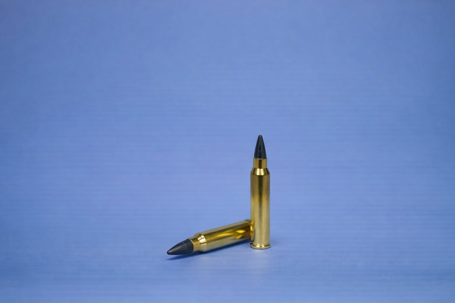 Two 5.56x45 SHATTER4K rounds, one standing upright and the other lying horizontally, displayed on a neutral background.