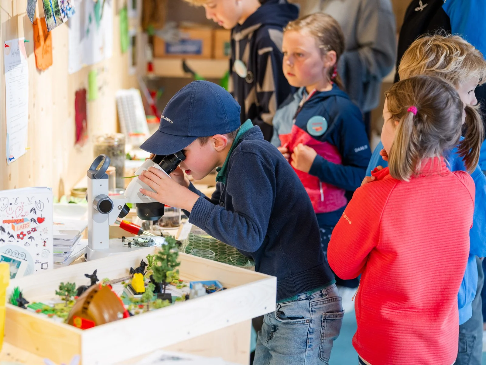 A child explores biodiversity through a microscope in a  supergut LAB