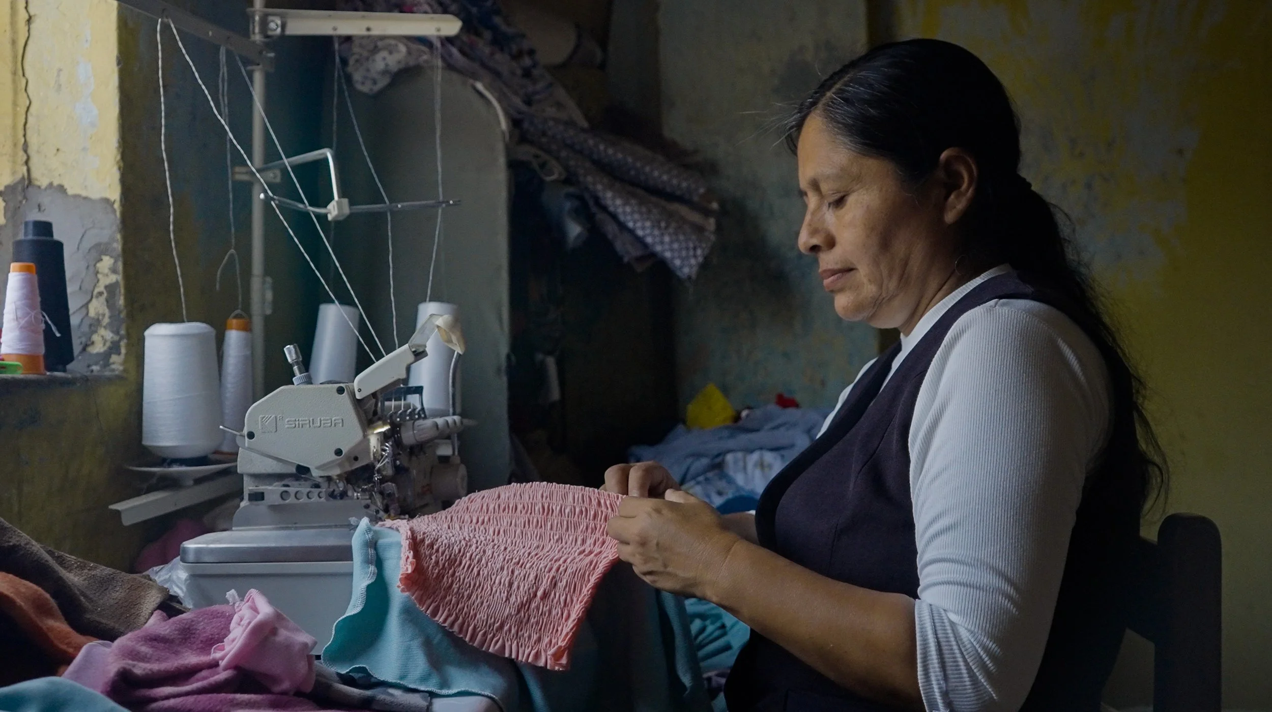 Woman sewing fabric with an industrial machine at home tailoring workshop.