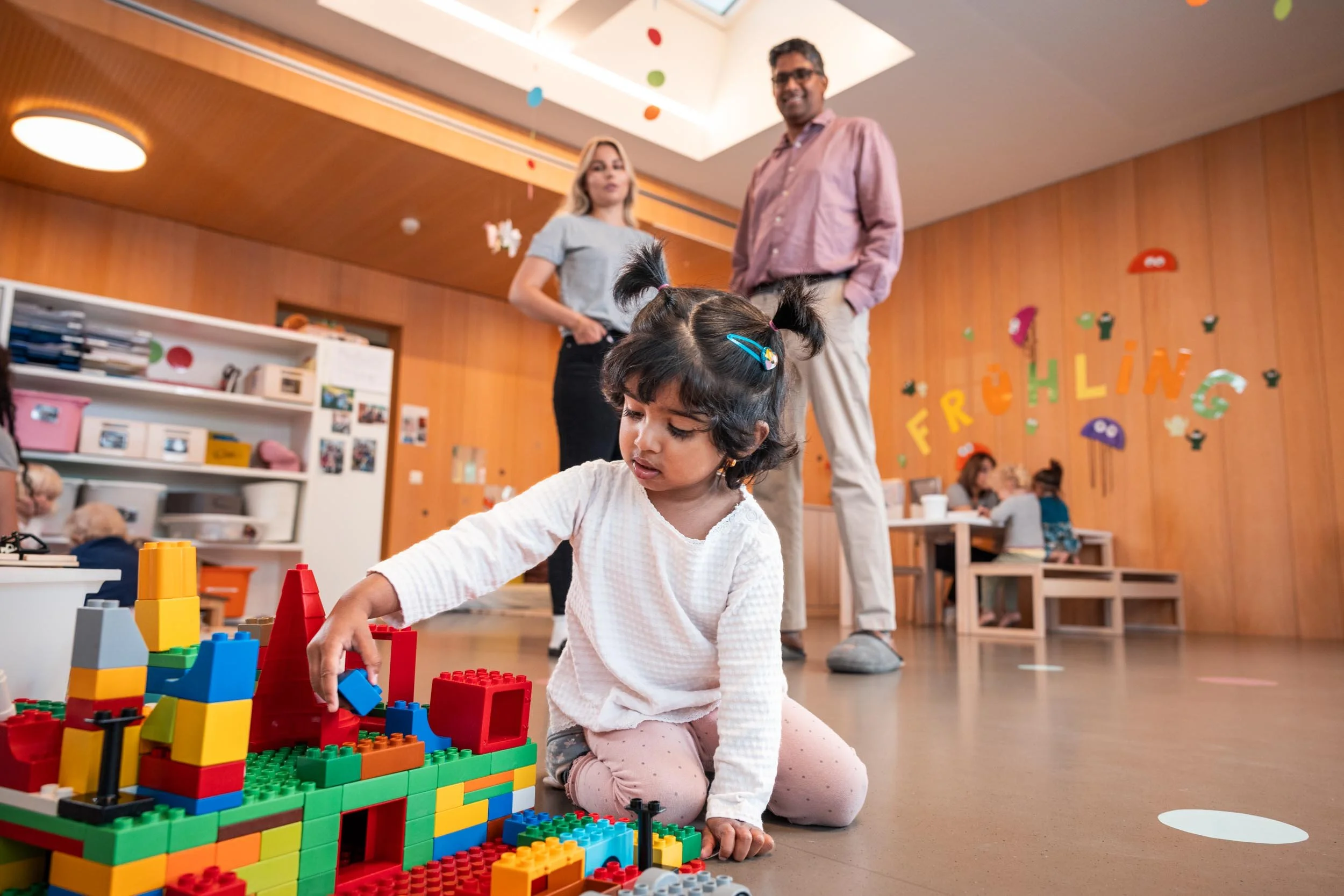 A child plays in a Hilti childcare center while his father talks to a caregiver.