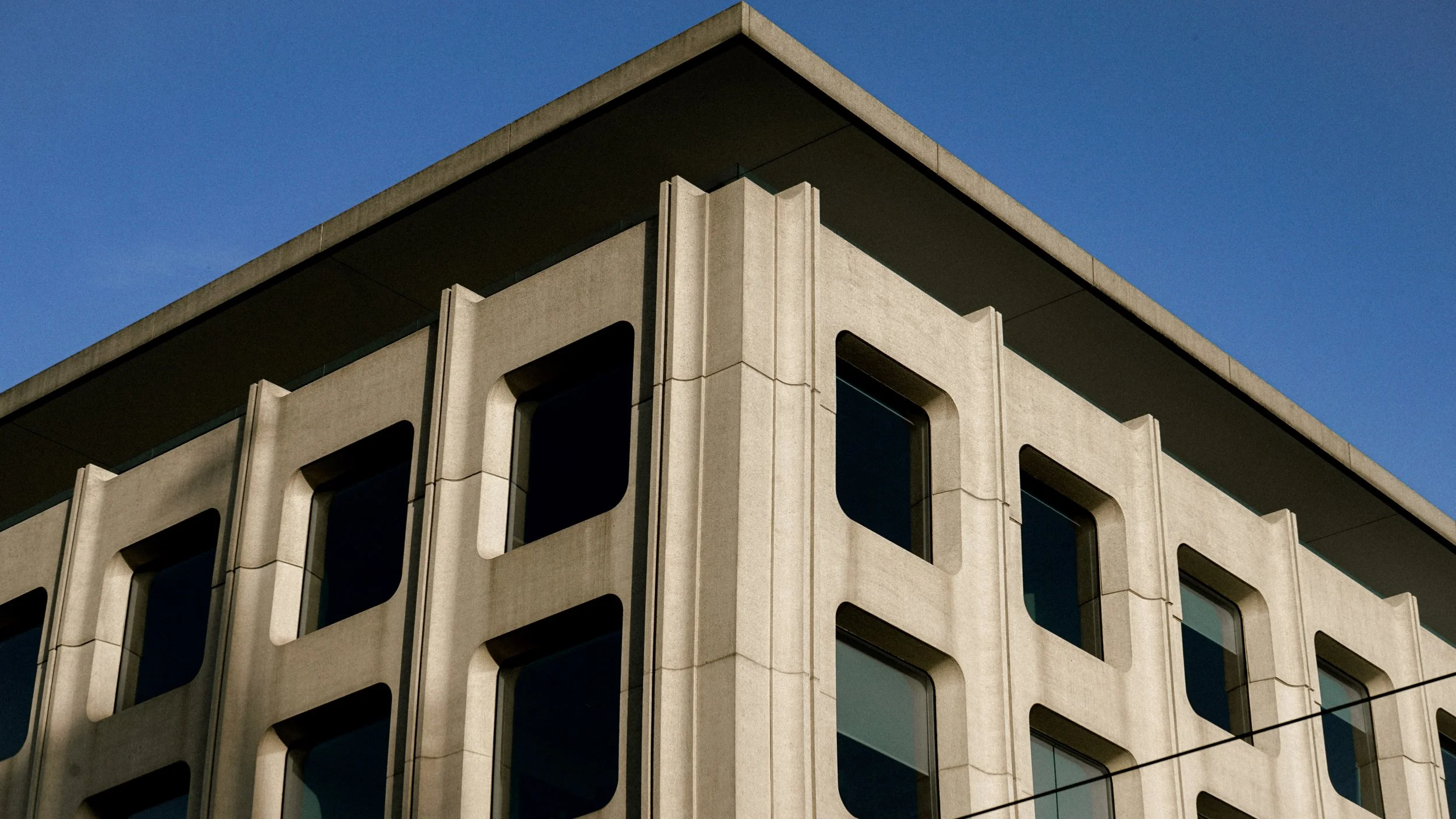 Façade d'un bâtiment moderne avec grandes fenêtres et structure en béton.