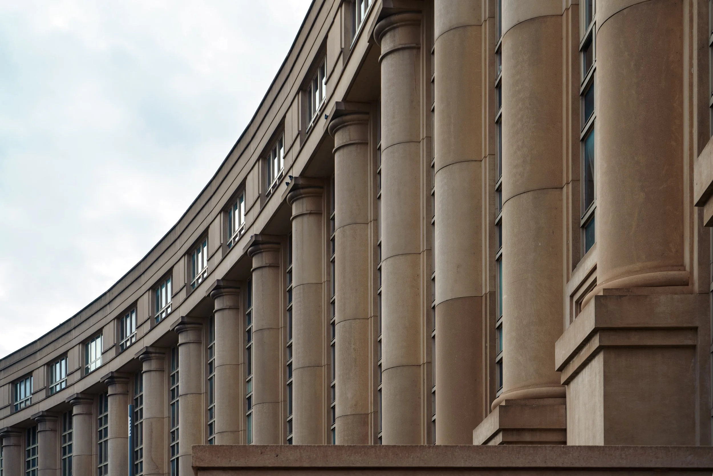 Façade d'un bâtiment classique avec des colonnes en pierre et des fenêtres alignées.