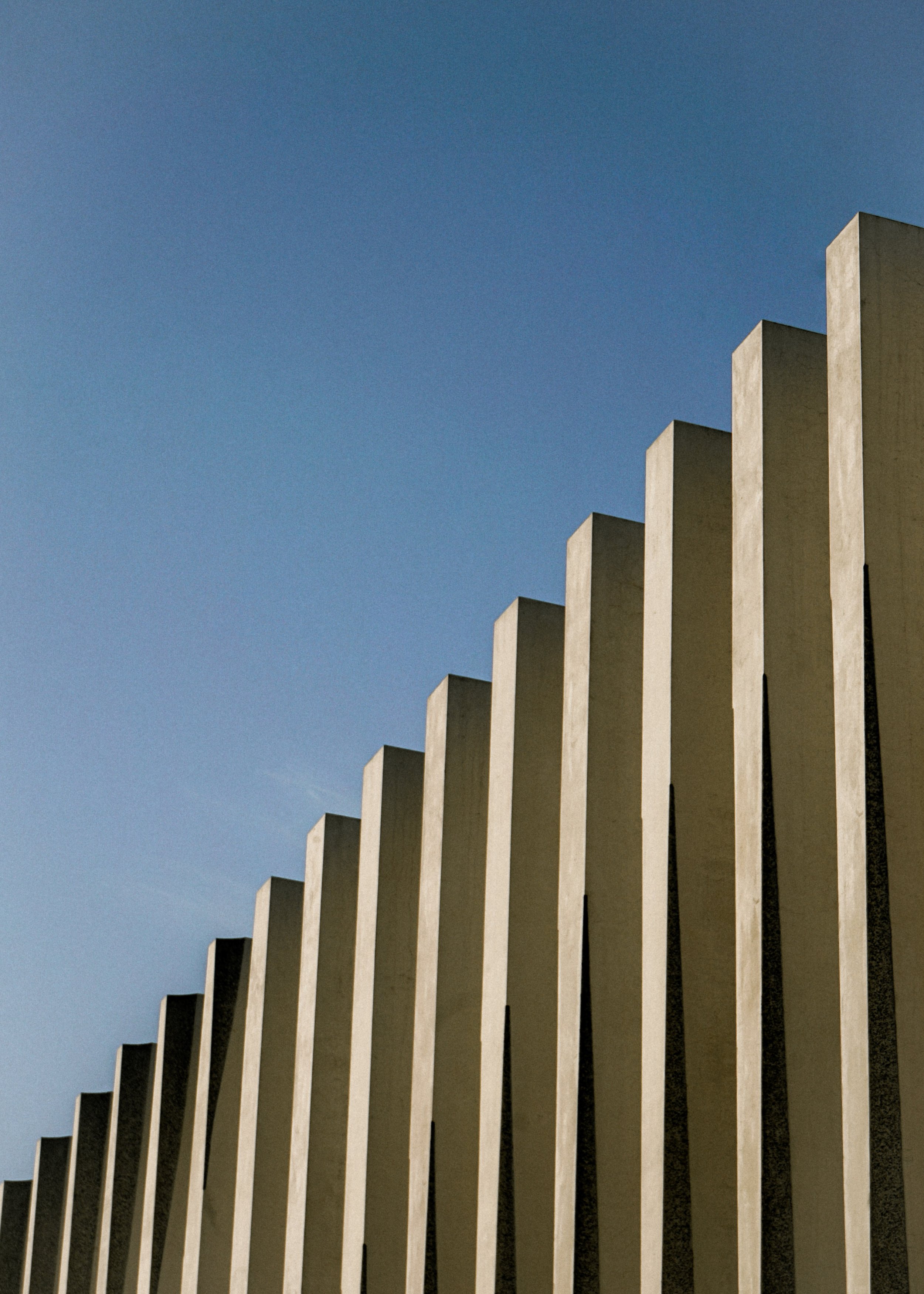 Façade moderne avec colonnes verticales sous ciel bleu.
