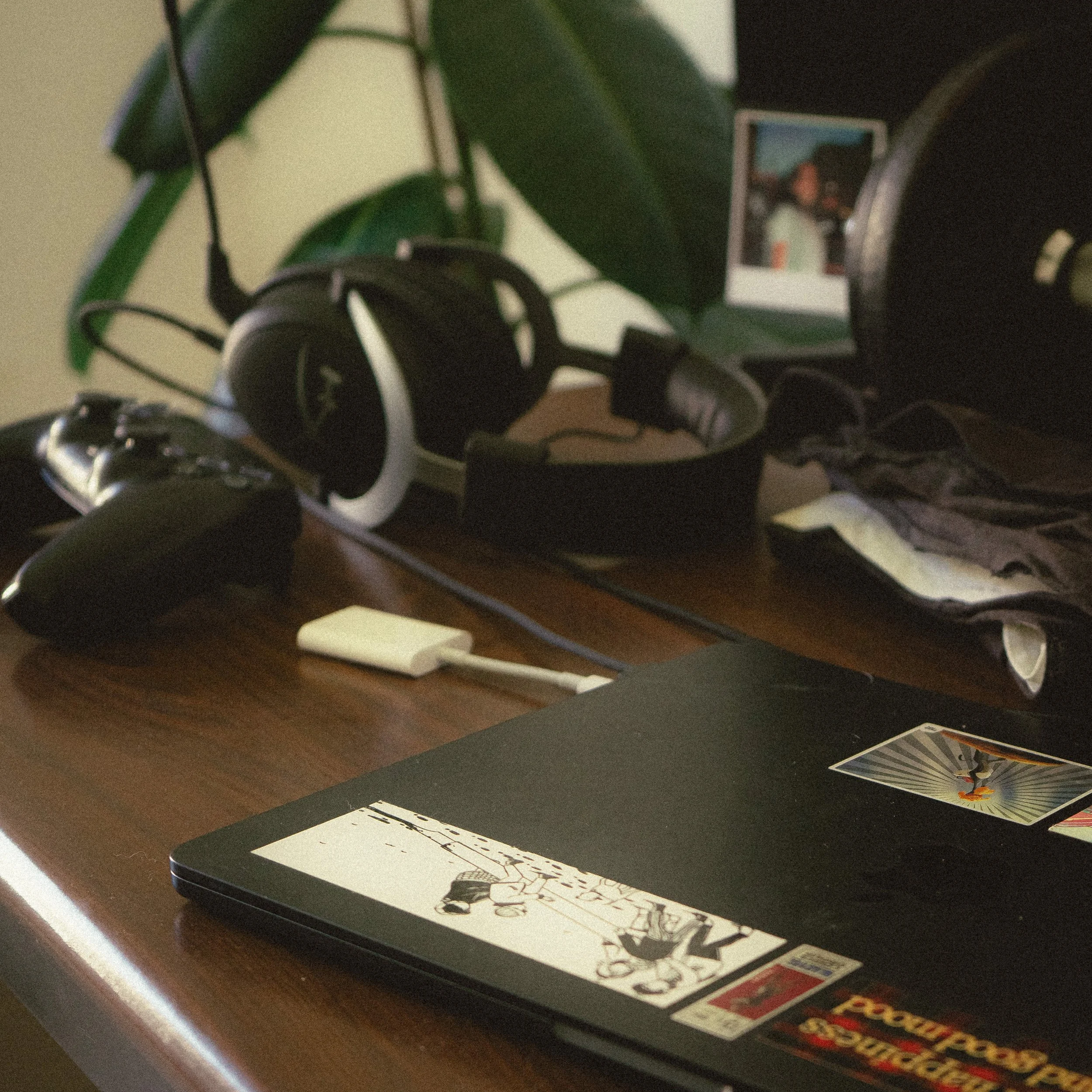 Bureau avec casque, manette de jeu, adaptateur, ordinateur portable avec autocollants