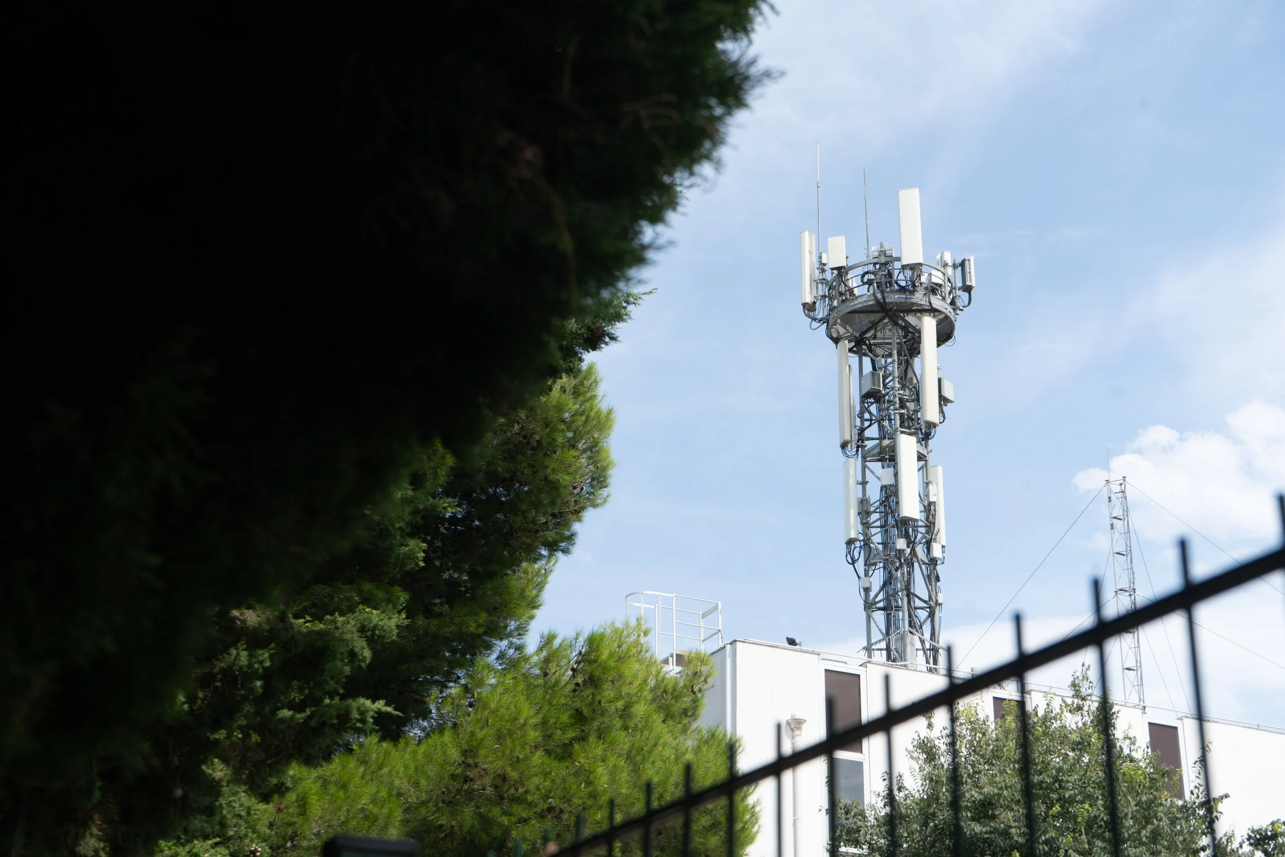 Antenne relais sur un bâtiment, entourée de végétation.