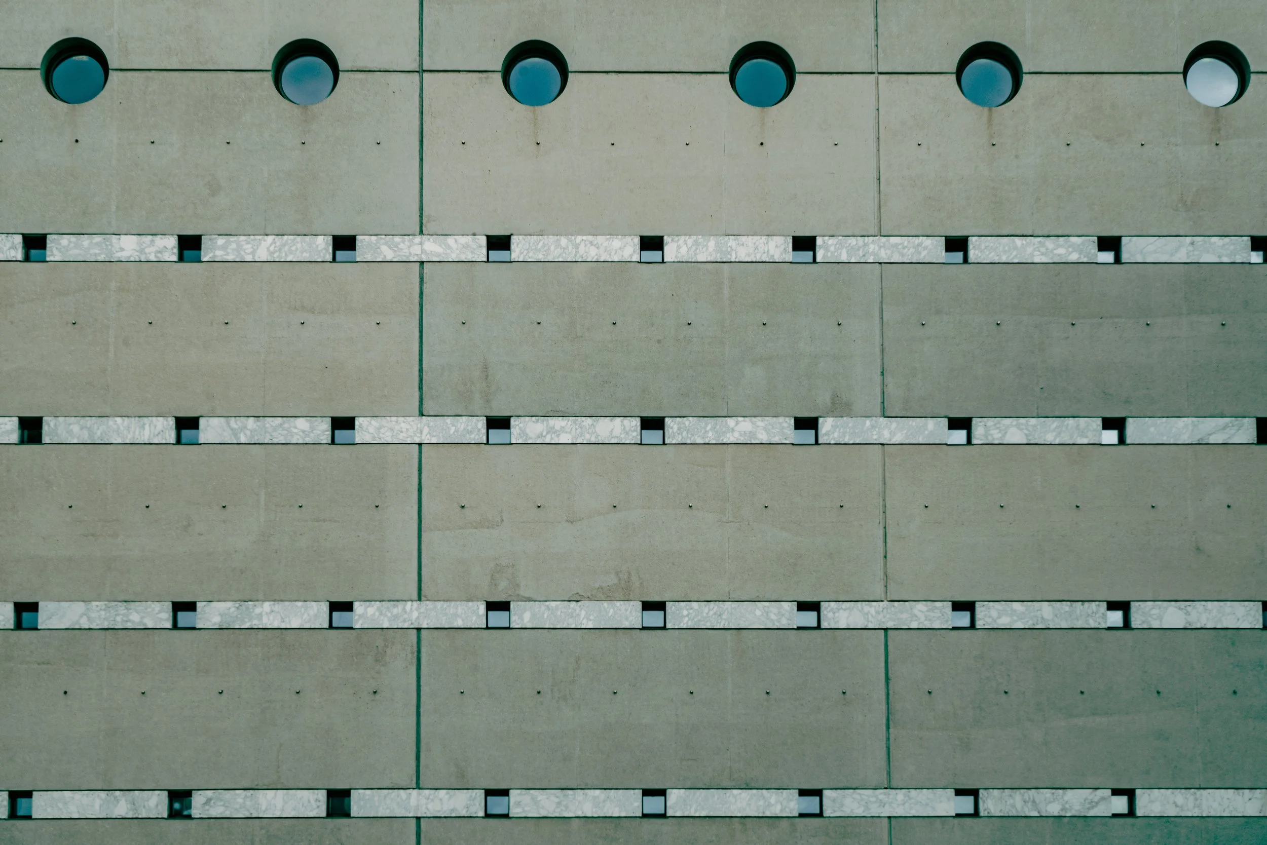 Mur en béton avec petites fenêtres rondes et rectangulaires