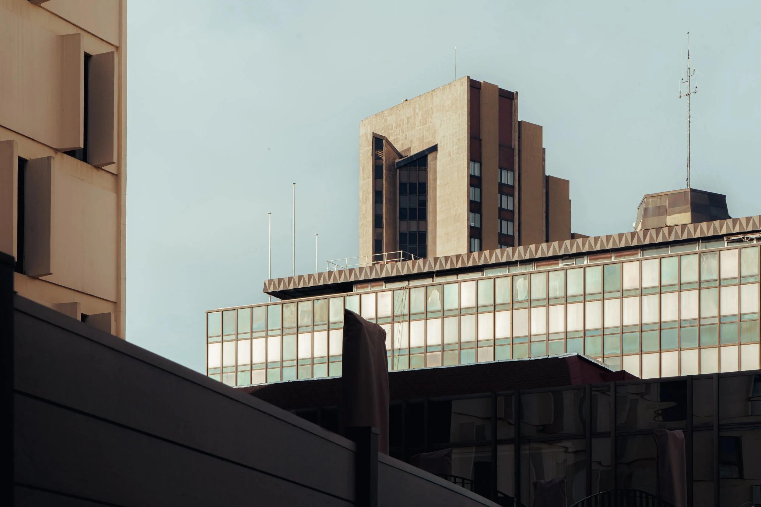 Bâtiments urbains avec fenêtres en verre et structure en béton sous un ciel clair.