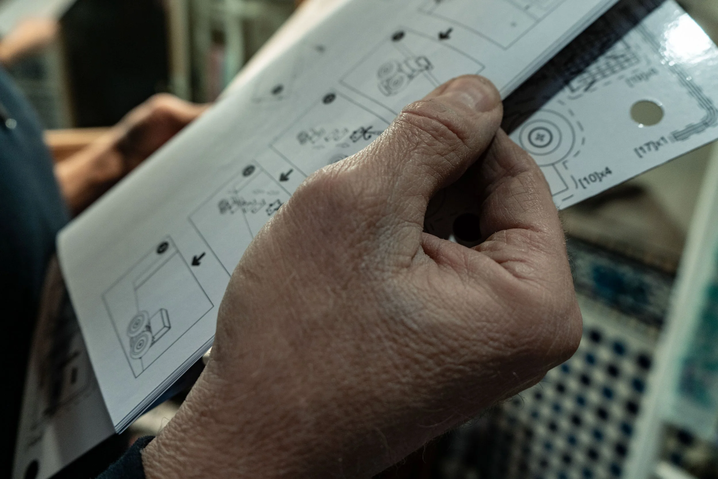 Une main tenant des feuilles de papier avec des schémas et des diagrammes.