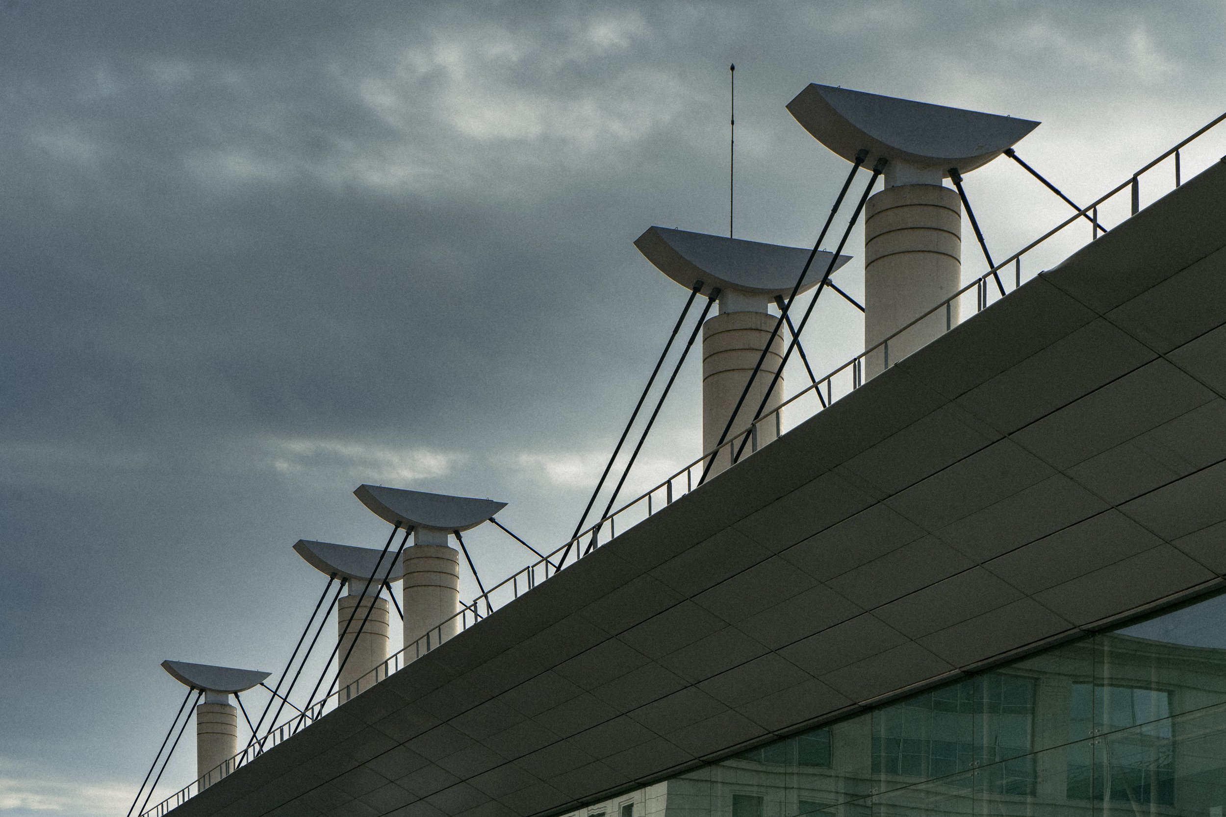 Toit moderne d'un bâtiment avec des installations métalliques contre un ciel nuageux.