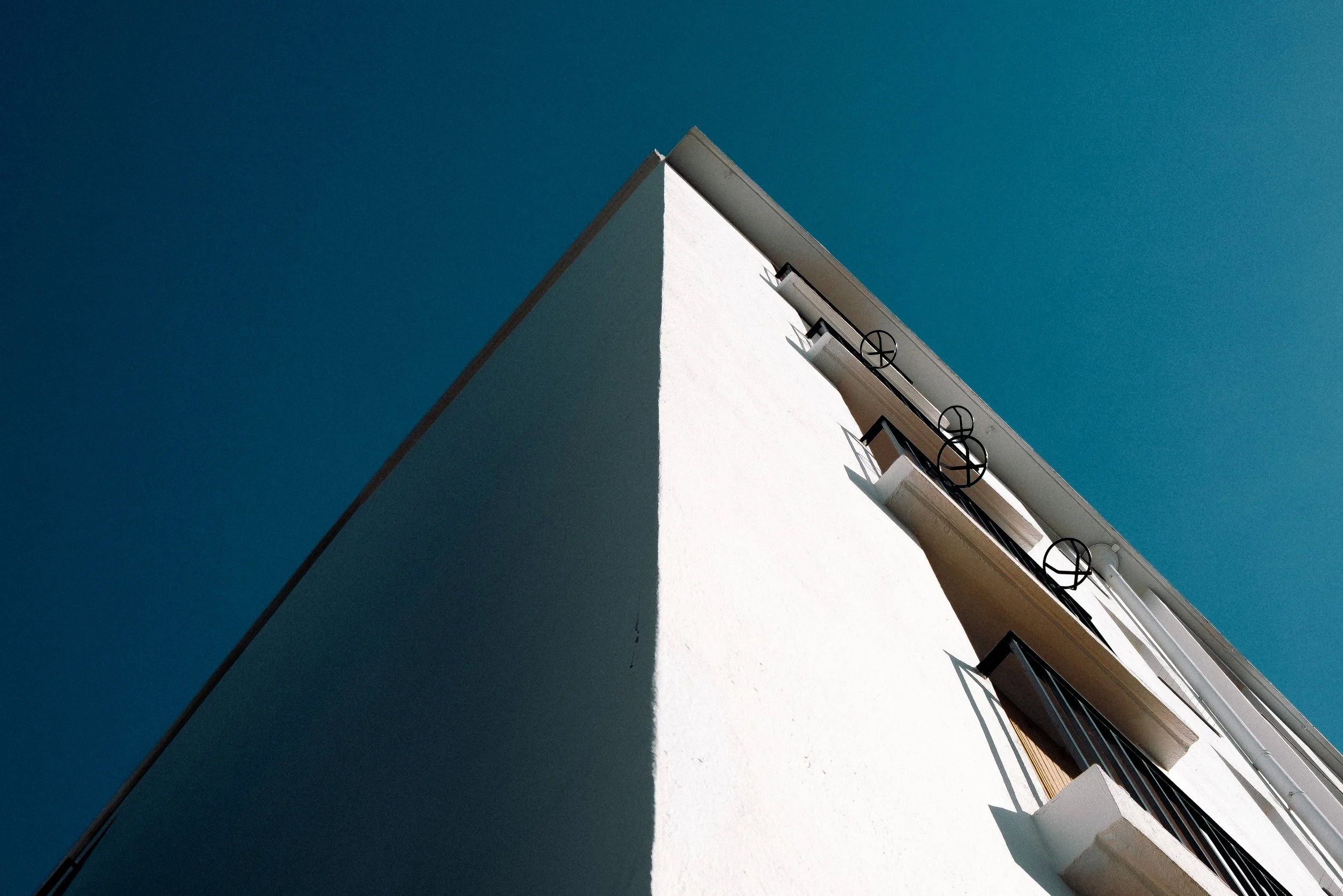 Vue en contre-plongée d'un bâtiment blanc avec un ciel bleu dégagé.