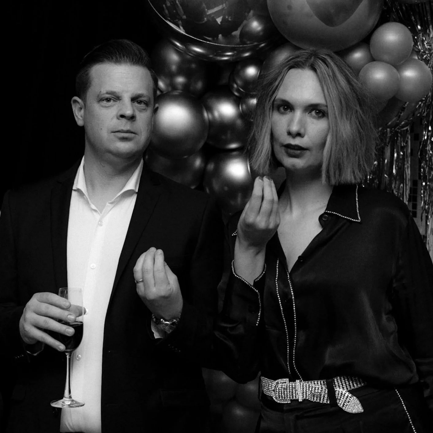 Black and white portrait of a man in a suit and a woman in a silk blouse at a corporate Christmas party.