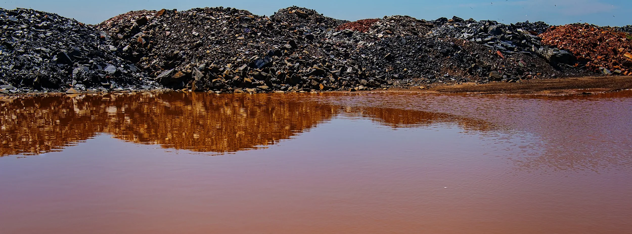 Mining wastewater stained by ferrous salts, indicated mineral pollution.