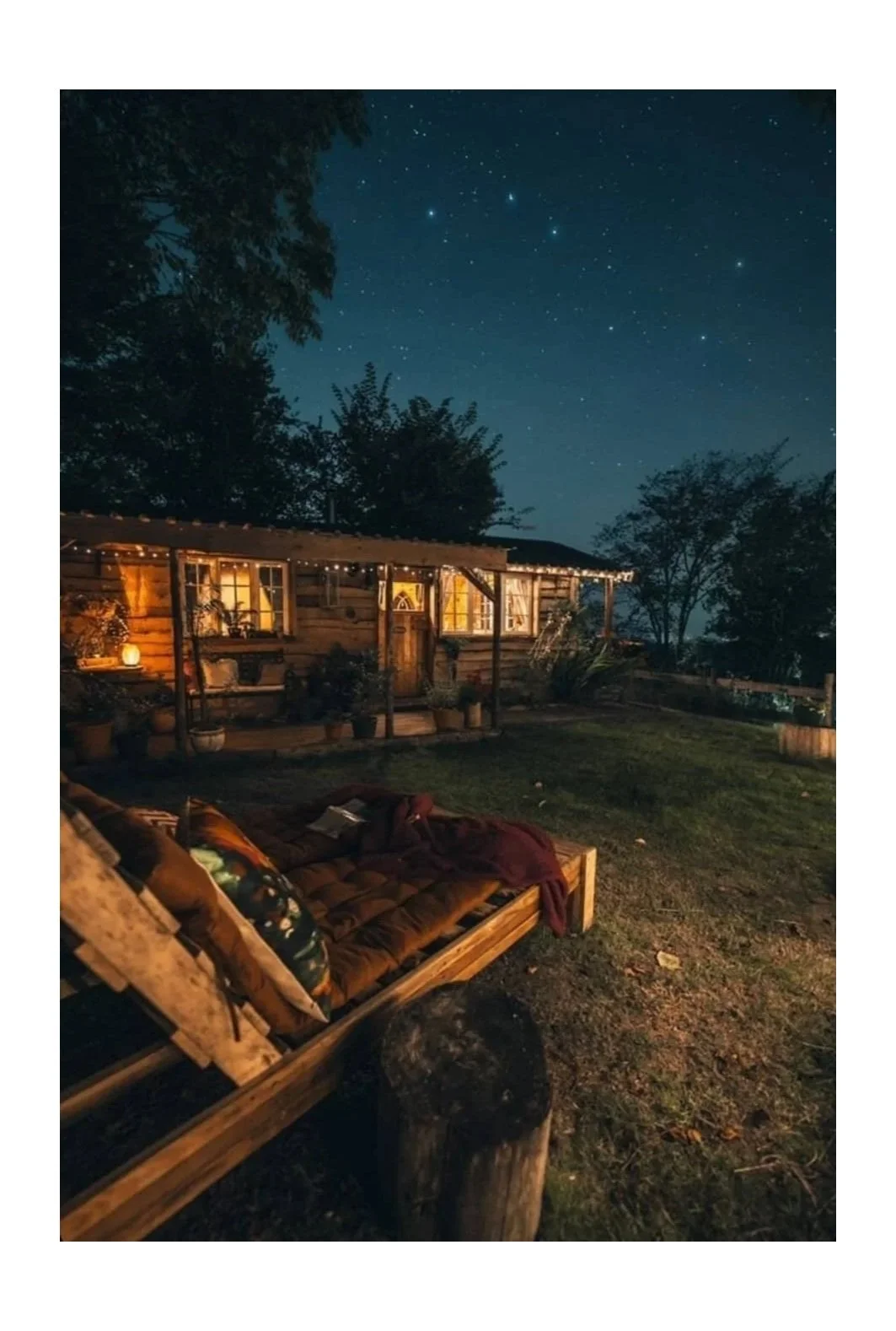 Cozy cabin at night with outdoor seating under a starry sky.