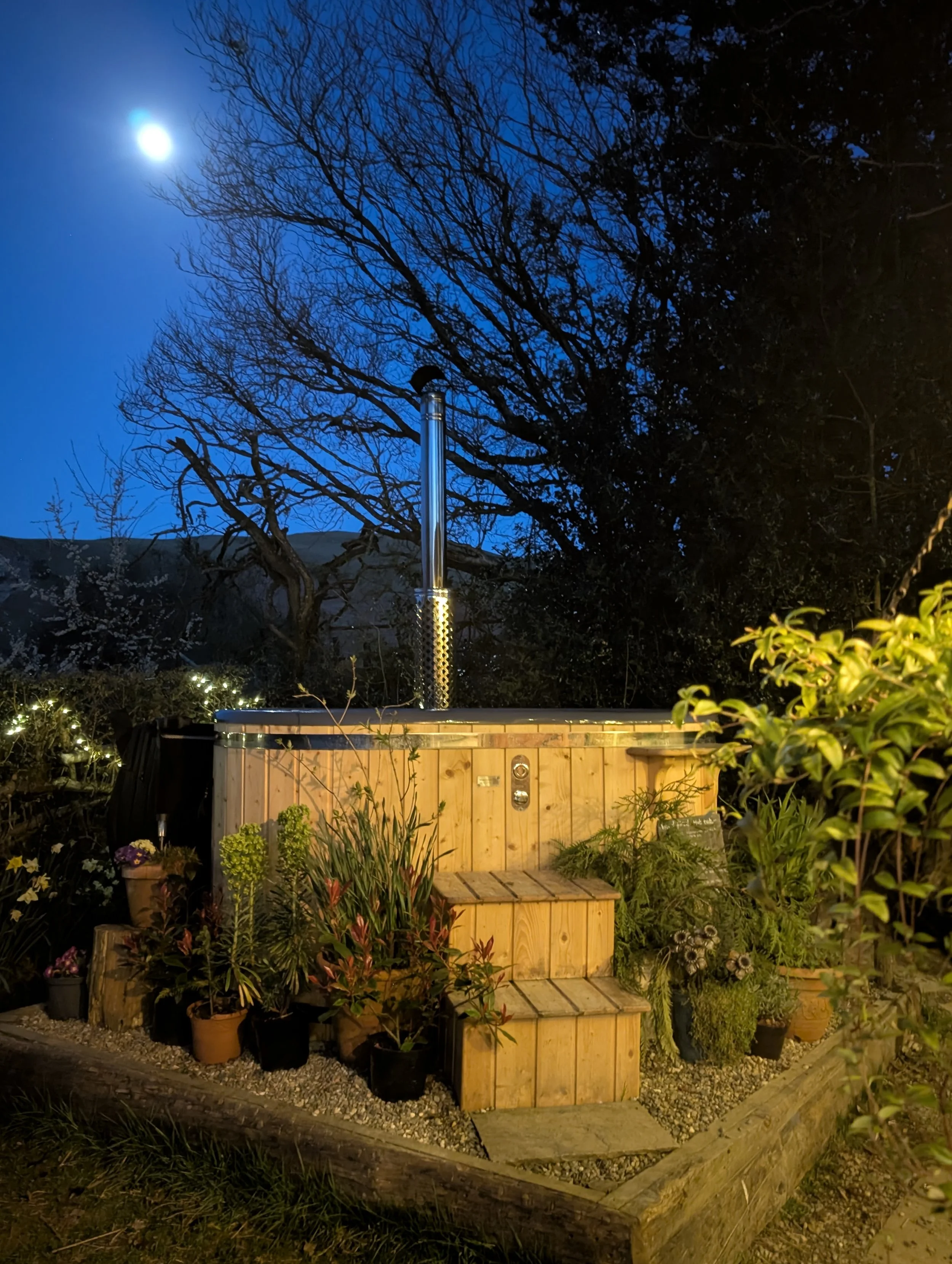 Wood-fired hot tub at Coety Bach under a starry night sky, ideal for a relaxing stargazing break in Wales