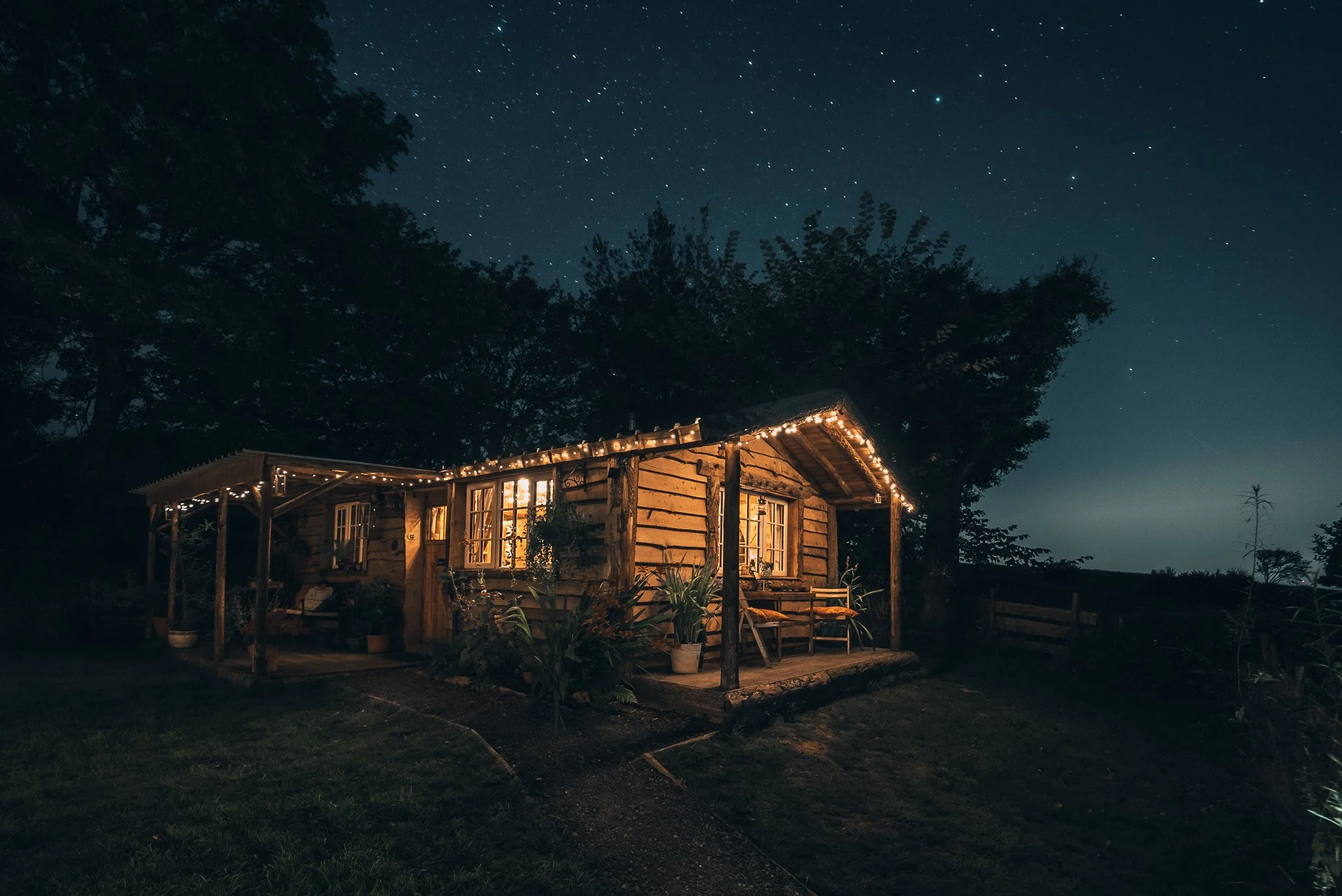 Cozy wooden cabin with string lights against a starry night sky.