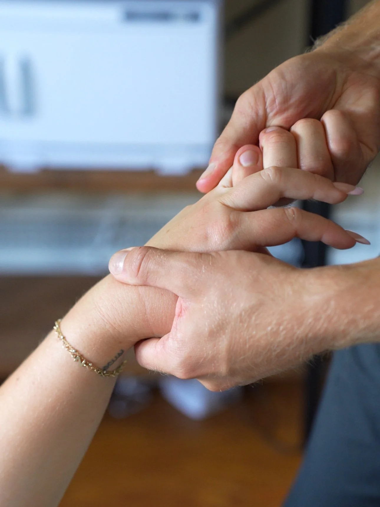 Two hands engaging in a handshake, with a focus on one hand wearing a delicate bracelet and a tattoo partially visible on the wrist.