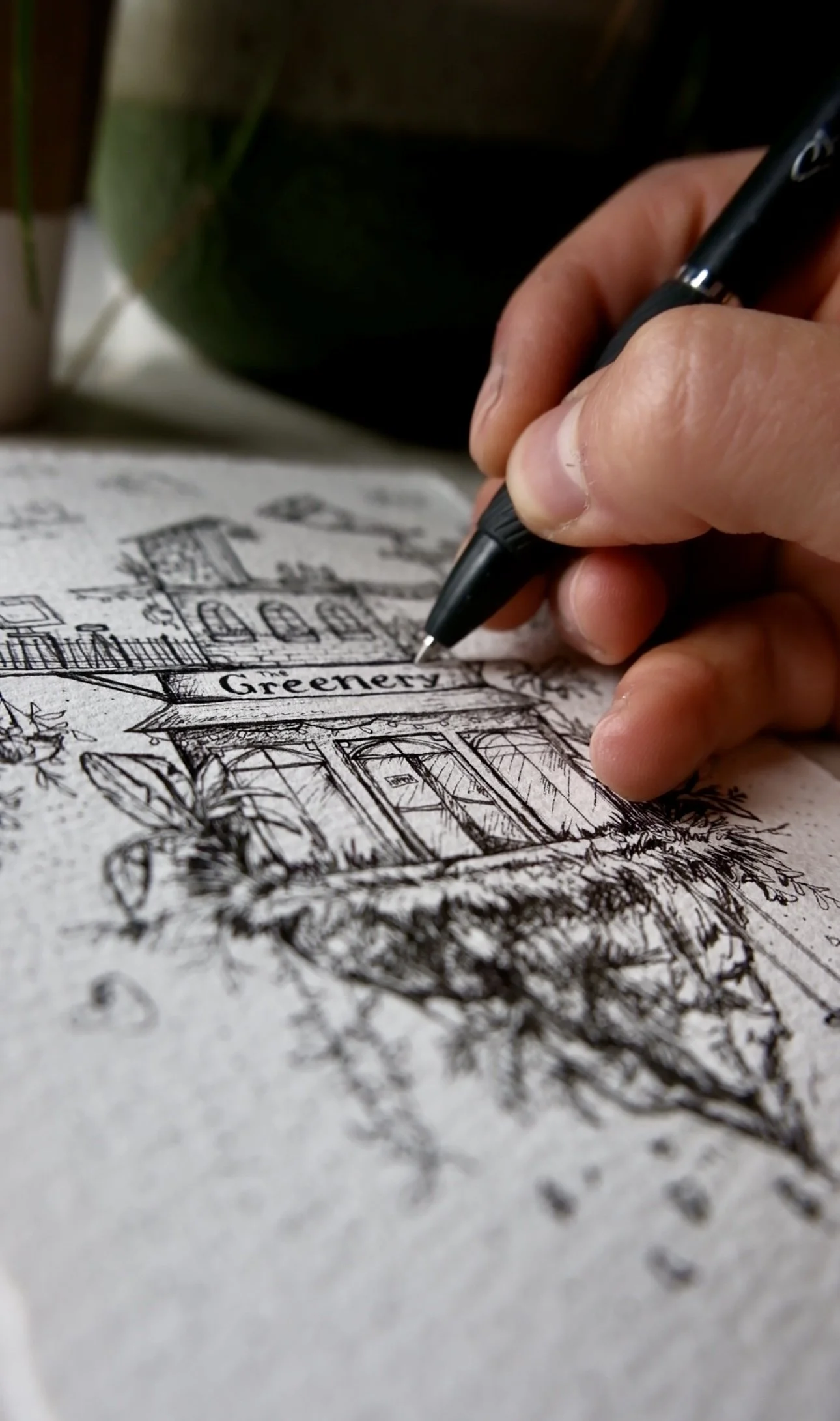Closeup of a hand holding a pen drawing on a rough paper