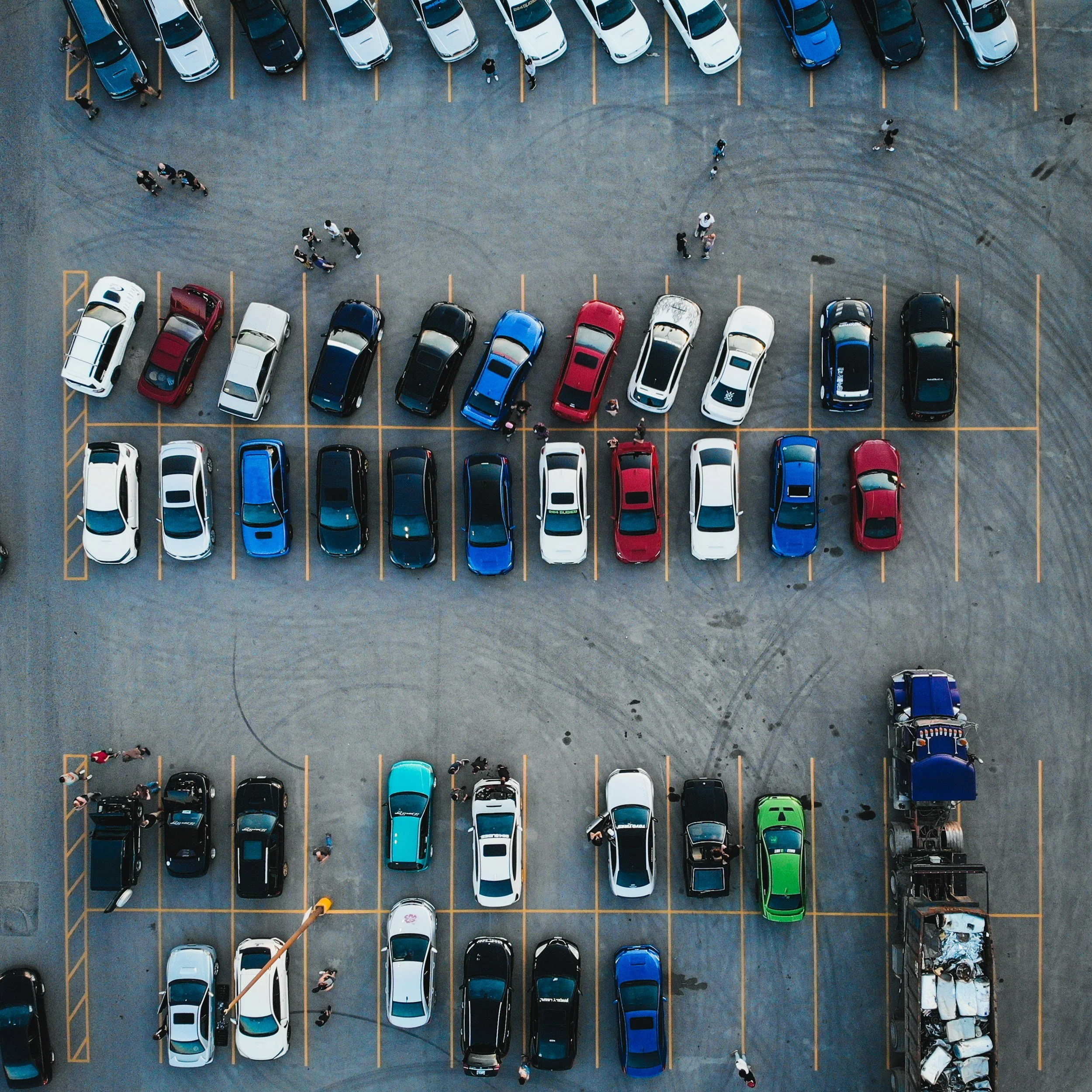 An aerial view of a parking lot with various cars parked in organized rows.