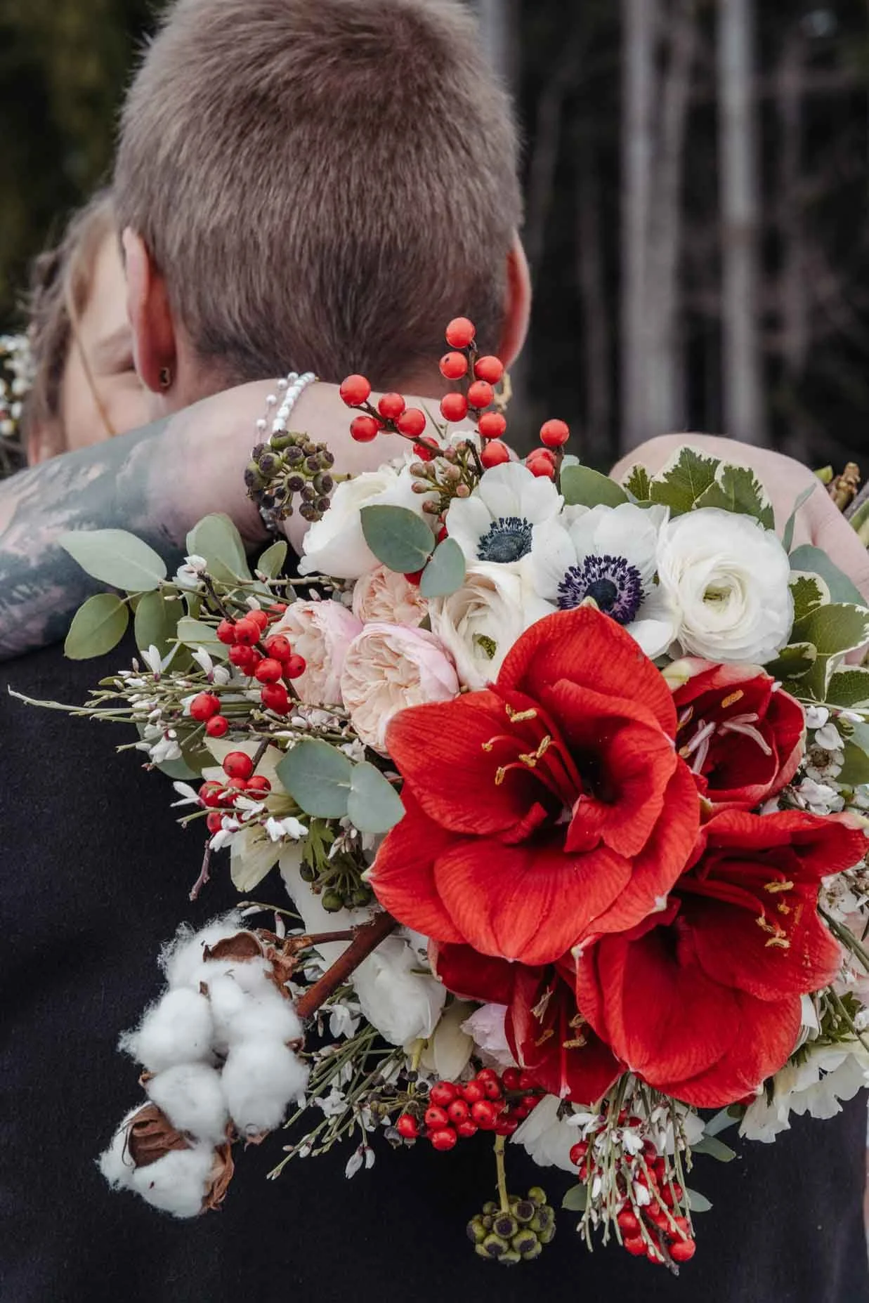 Wunderschöner Winter Brautstrauss mit roten Amaryllis, weißen Anemonen, Rosen, Beeren und Eukalyptus.