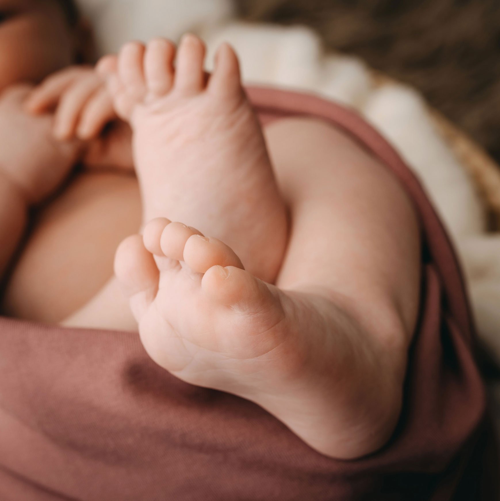 Nahaufnahme von Babyfüssen in einer Decke gewickelt.
