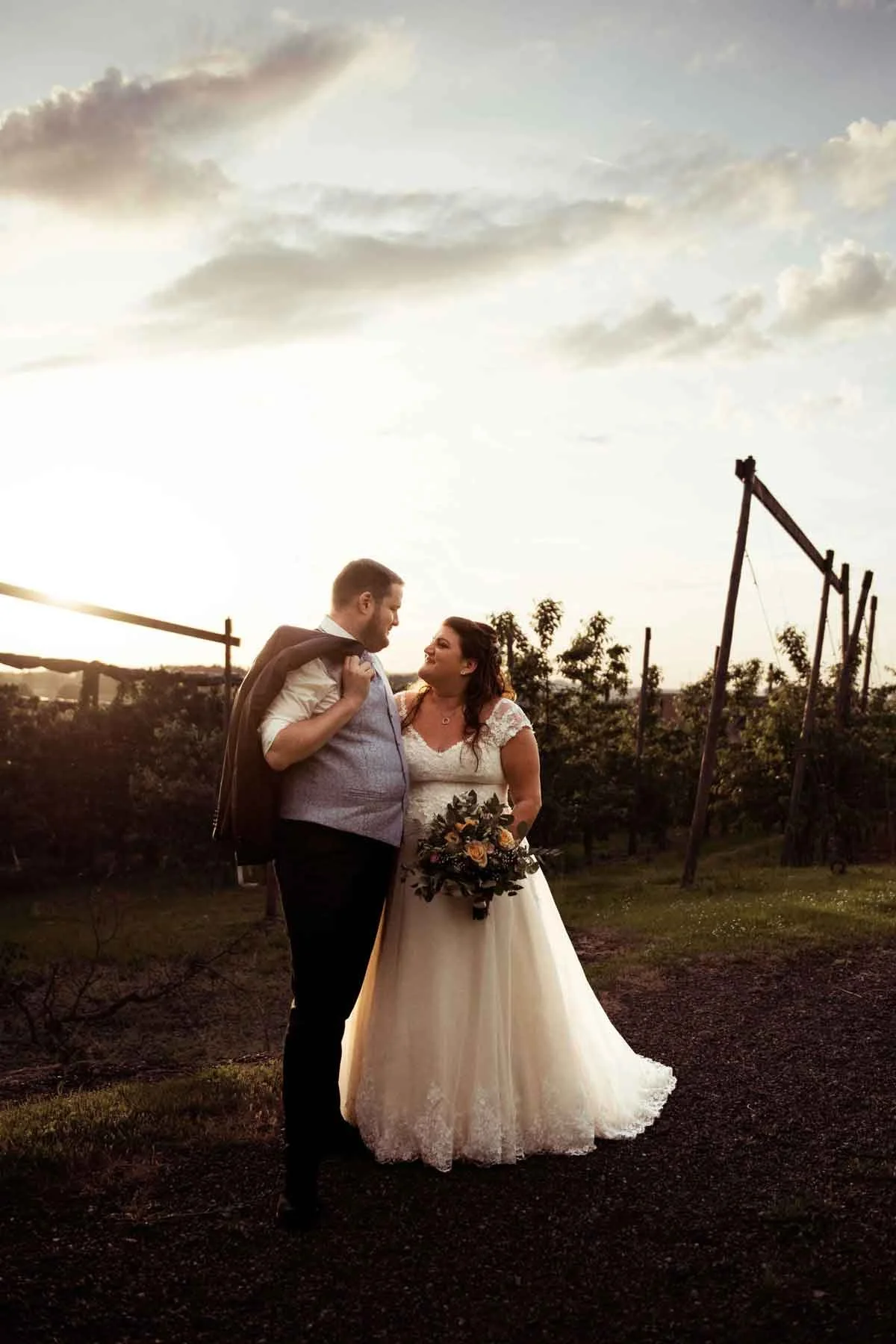 Brautpaar bei Sonnenuntergang im Freien die sich liebevoll ansehen.