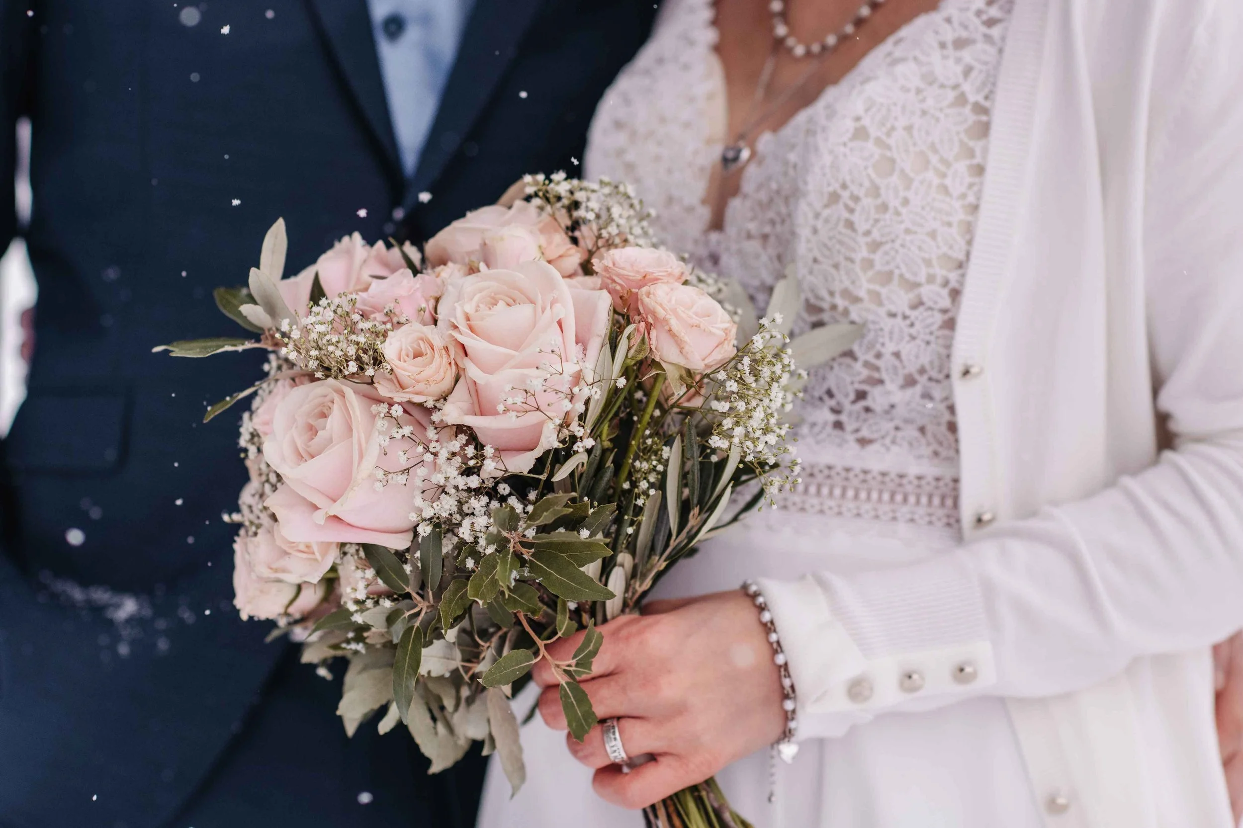 Braut hält einen Blumenstrauss aus rosafarbenen Rosen bei einer Brautpaarshooting.