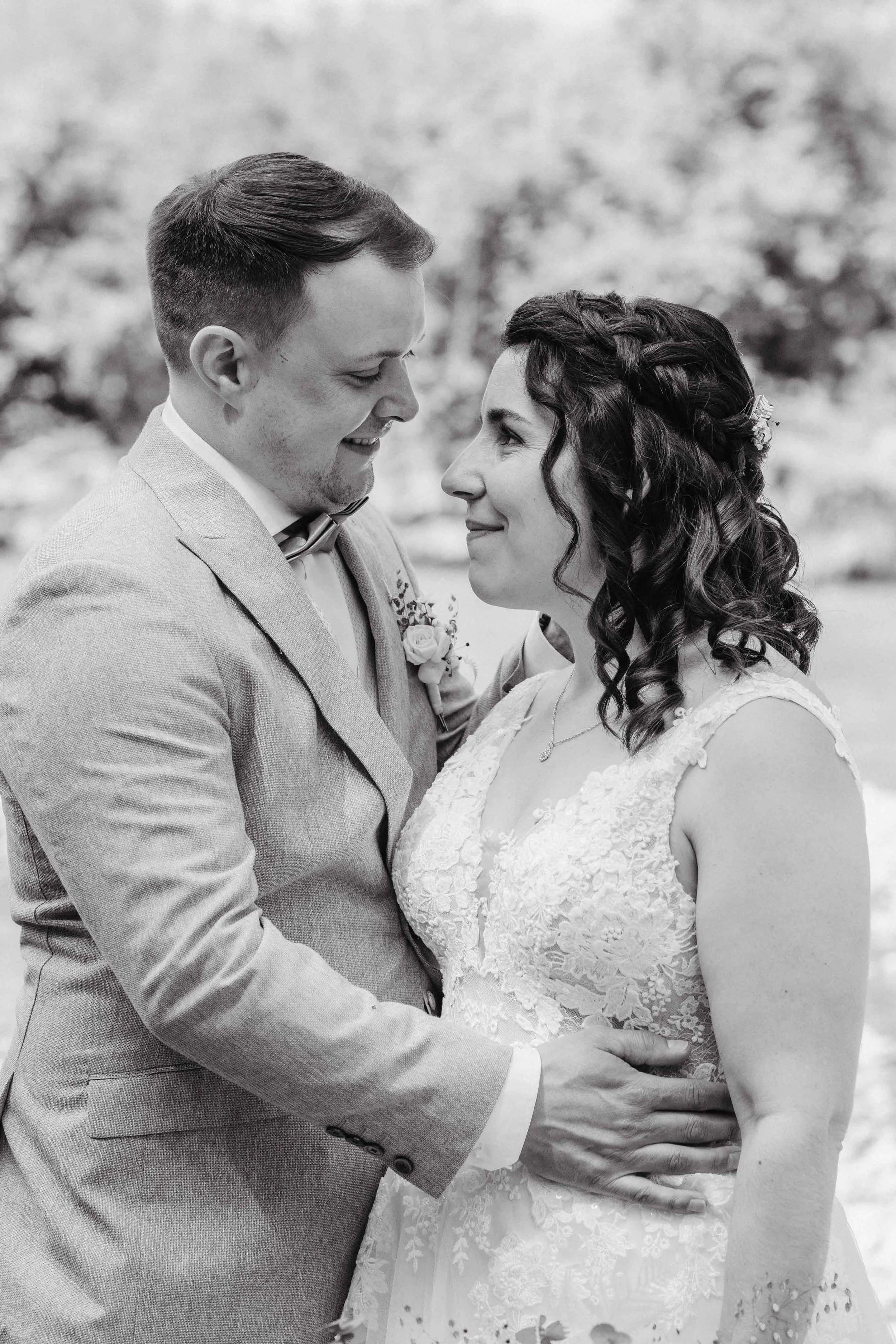 Brautpaar schaut sich liebevoll an, im Freien, schwarz-weiß Fotografie.