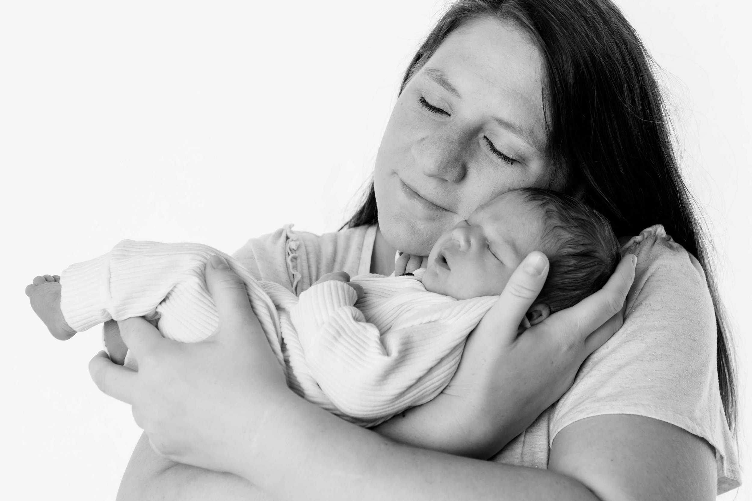 Eine Frau hält ein neugeborenes Baby im Arm, beide mit geschlossenen Augen.